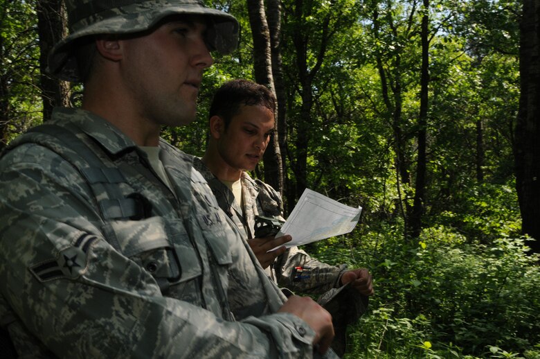 Staff Sergeant Mitch Pitoscia and Airman 1st Class Corey Pitoscia, members of the Security Forces Squadron, 148th Fighter Wing, Duluth, Minn., consult their map and compass as they make their way through the land navigation course at Camp Ripley, Minn. on June 5, 2011.  The land navigation course tests the ability to plot out a course prior to entering the woods, but also the ability to stay on that course despite difficult terrain.  (U.S. Air Force Photo by Tech. Sgt. Scott Herrington)