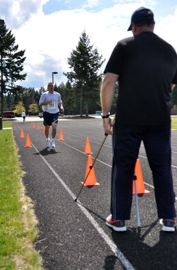 Patrick Conway, right, 62nd Medical Squadron exercise physiologist and fitness program manager, films a runner during the McChord Health and Wellness Center running clinic May 23 at Joint Base Lewis-McChord, Wash. After completing their warm-up lap, runners sprint a 50-meter stretch. (U.S. Air Force photo/Airman 1st Class Leah Young)
