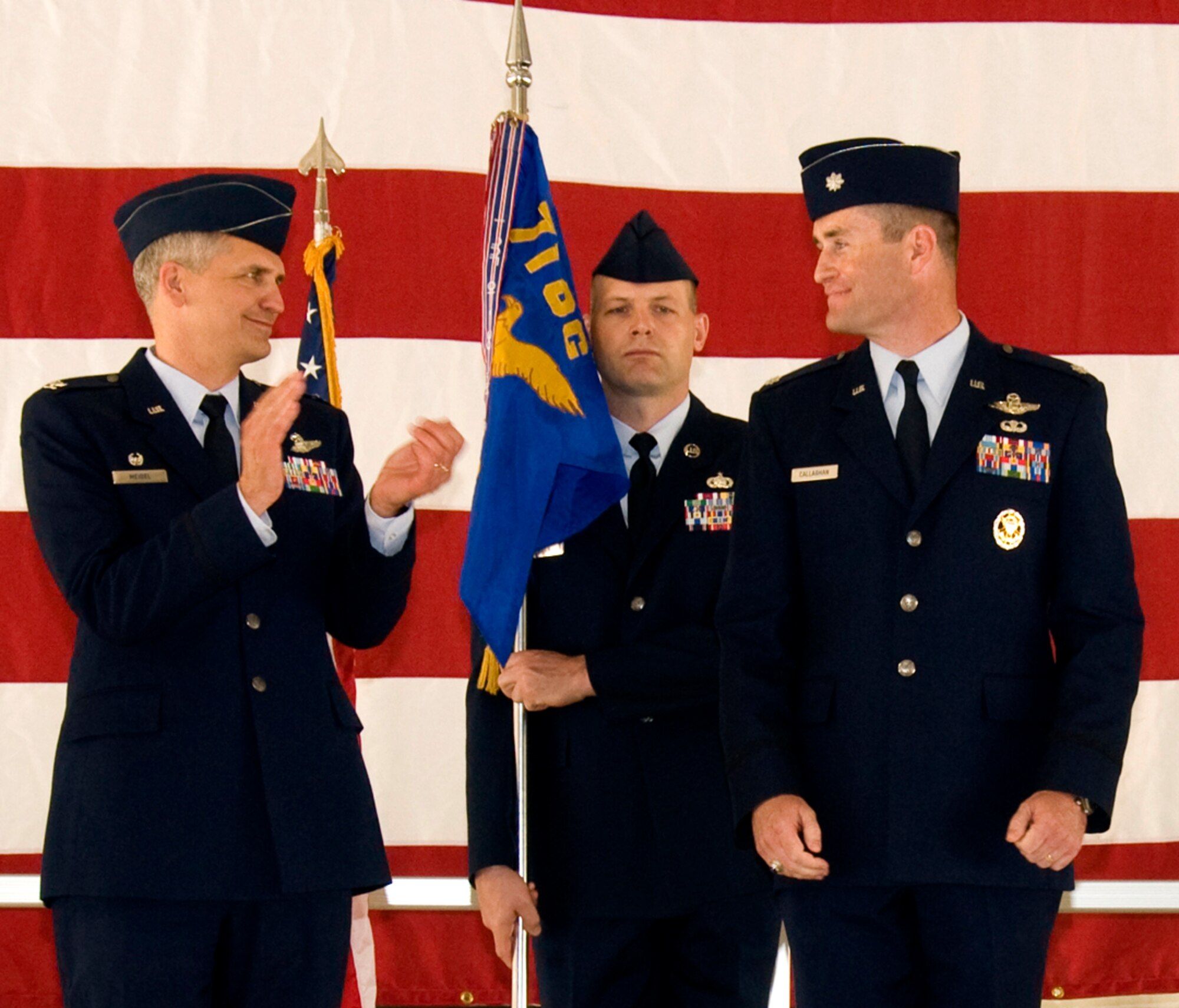 Col. Kurt Meidel, left, 71st Operations Group commander, congratulations Lt. Col. Chris Callaghan, right, upon taking command of the 71st Operations Support Squadron, during a change of command ceremony held Friday, June 3, in Hangar 199 at Vance AFB, Okla. Holding the 71st OG guidon, center, is Master Sgt. Scott Swain, the group first sergeant. Colonel Callaghan replaced Lt. Col. David Merritt, who will attend Air War College in residence at Maxwell AFB, Ala. (U.S. Air Force photo/ Roger Betz)