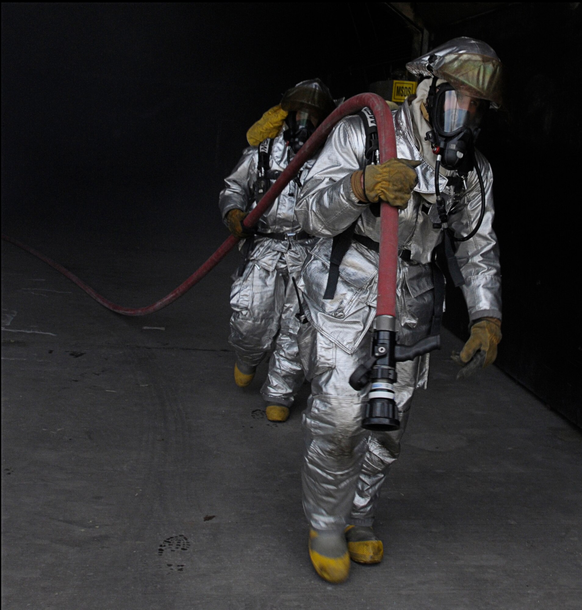 U.S. Air Force Staff Sgt. Brent Watkins and Airman 1st Class Ronald Brown, 31st Civil Engineer Squadron, Aviano Air Base, Italy, retrieve their gear used for a simulated fire during Silver Flag, Ramstein Air Base, Germany, June 7, 2011.  Silver Flag is a weeklong training program for Airmen from various bases; it combines classroom and practical application exercises to prepare Airmen for deployment. (U.S. Air Force photo by Airman 1st Class Desiree Esposito)
