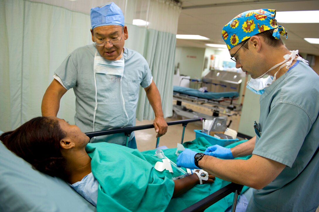 Osvaldo Romero, left, from Latter-day Saint Charities, talks to a patient while U.S. Navy Lt. Cmdr. James Solomon preps her for surgery aboard the USNS Comfort in Tumaco, Colombia, June 5, 2011. Solomon is a Navy anesthesiologist.