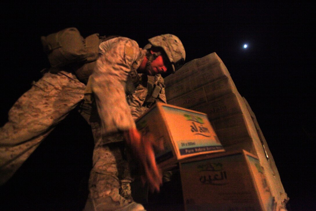 Lance Cpl. Luke Stauber, a motor transportation operator with Regimental Combat Team 8, hands a case of water off to another Marine during a resupply mission to the village of Washir, Afghanistan, June 8. The mission brought food, water and fuel to the Afghan National Army soldiers of the 1st Kandak, 2nd Brigade, 215th Corps, during their mission to secure the town and establish a presence in the area.