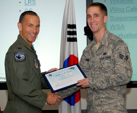 KUNSAN AIR BASE, Republic of Korea -- Col. Scott Pleus, 8th Fighter Wing commander, presents Senior Airman Steven Stiehl, 8th Aircraft Maintenance Squadron aircraft electrical and environmental systems journeyman, with a Pride of the Pack award here June 9. (U.S. Air Force photo/Capt. Sheryll Klinkel)