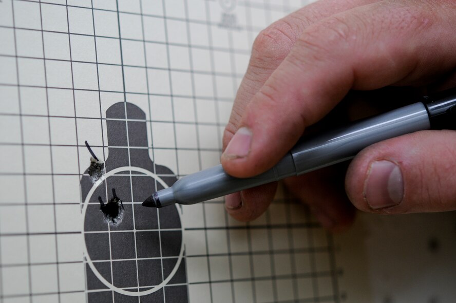 An 18th Security Forces Squadron Combat Arms instructor indicates on-target shots on a zeroing target after making sight corrections at the CA firing range June 1. CA instructors use such targets to set each qualifying Airman's weapon to their personal firing style, making them a more accurate fighting force. (U.S. Air Force photo/ Airman 1st Class Maeson L. Elleman)