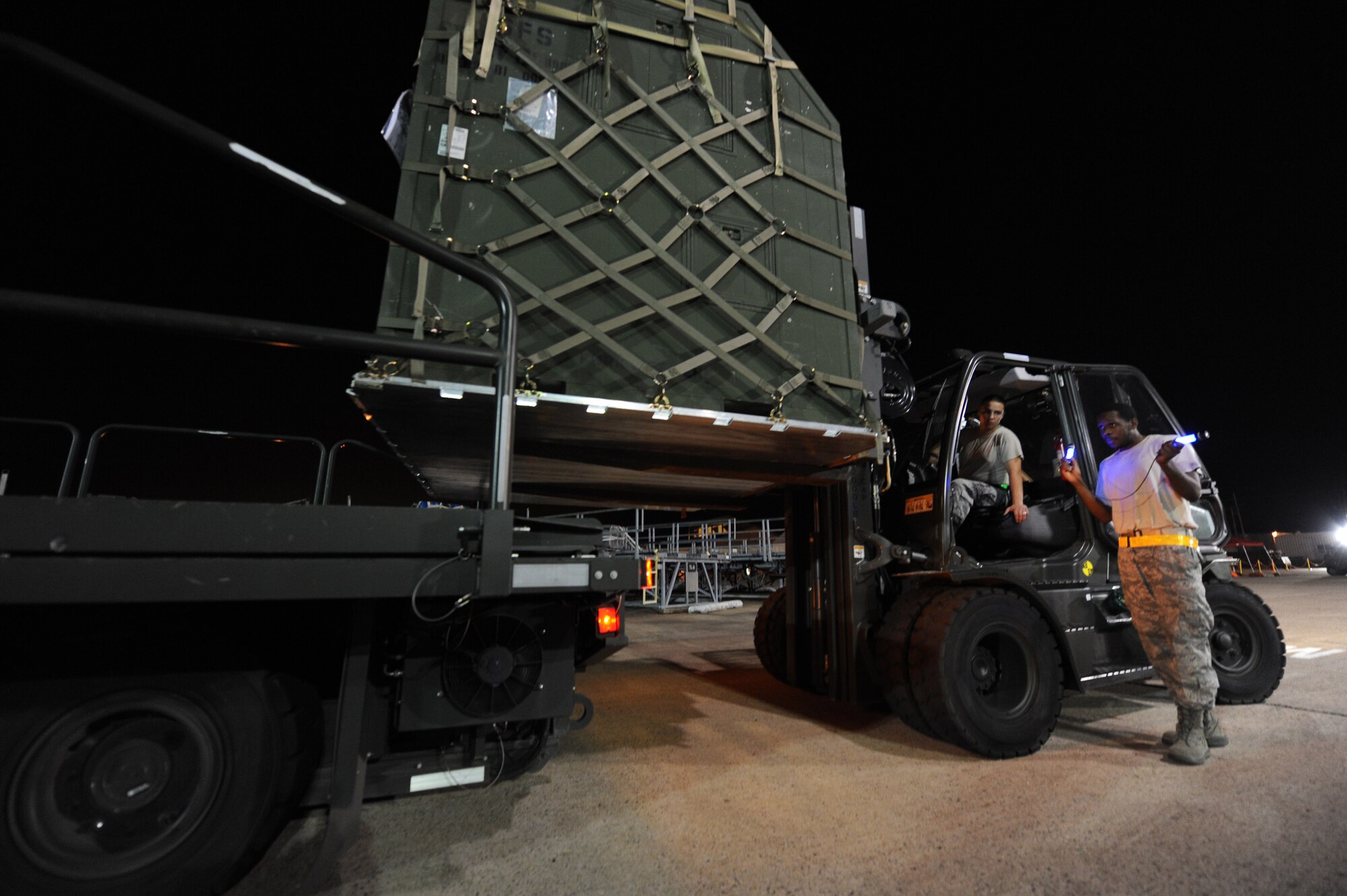 Senior Airman Cornelius Wilkerson (right) gives directions to Senior Airman Adrian Montoya as he drives a forklift June 4, 2011, on Little Rock Air Force Base, Ark.  Airmen Wilkerson and Montoya, both air transportation journeymen with the 19th Logistics Readiness Squadron, supported an operational readiness exercise by loading equipment, storage containers and pallets of baggage onto C-130 aircraft. (U.S. Air Force photo by Tech. Sgt. Chad Chisholm)