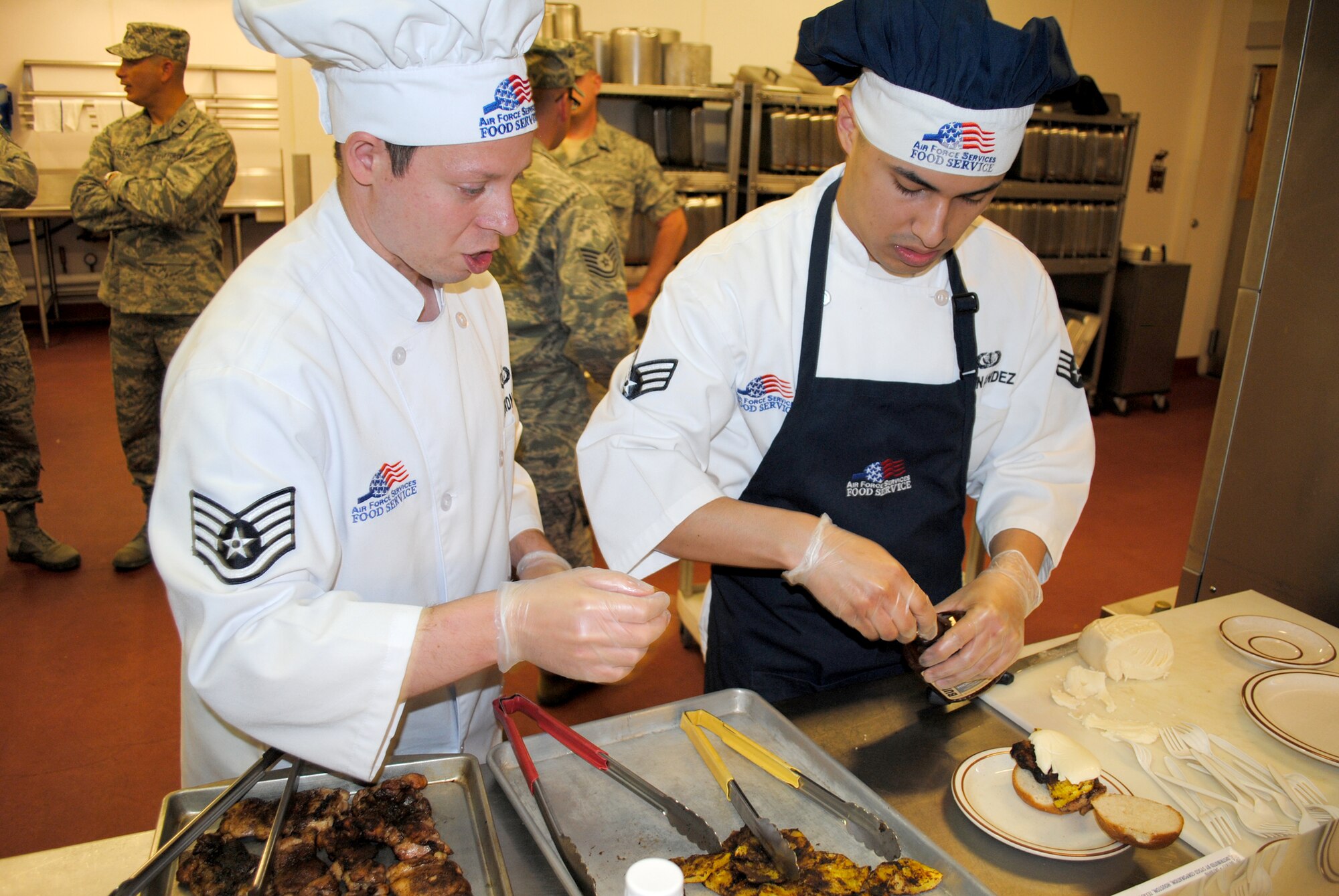 Staff Sgt. Will Gardner and Senior Airman Frank Hernandez, both missile chefs with the 12th Missile Squadron, add the finishing touch to their dish - barbecue sauce.  They were one of four teams that participated in the Warrior Chef Competition June 2.  (U.S. Air Force photo/Airman Cortney Hansen)