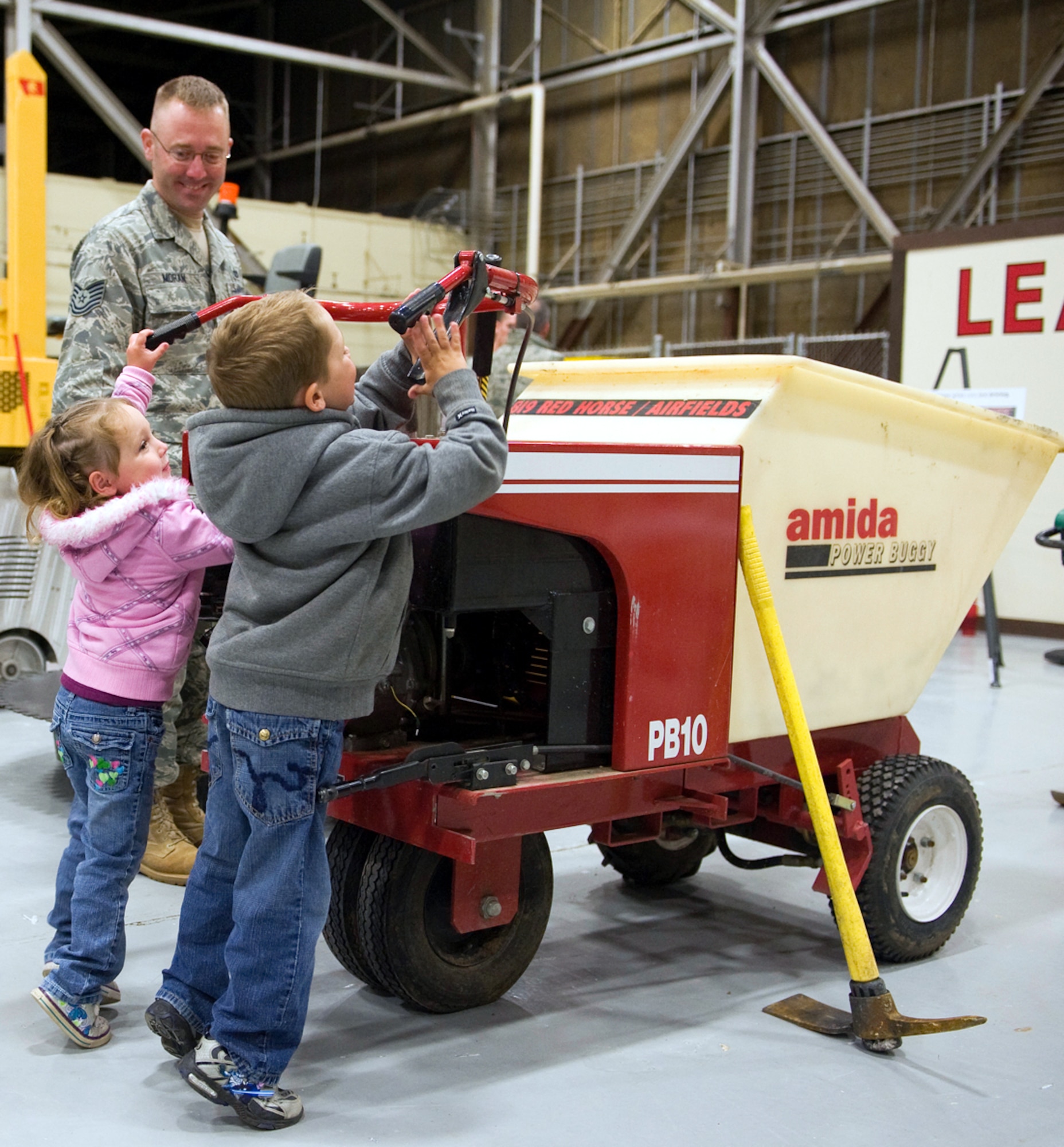 Tech. Sgt. Ryan Moran, 819th RED HORSE Squadron heavy equipment operator, lets his children Olivia, 3, and Brady, 5, try out the powered concrete hauler, during the 819th RHS open house, June 3. (U.S. Air Force photo / Beau Wade)