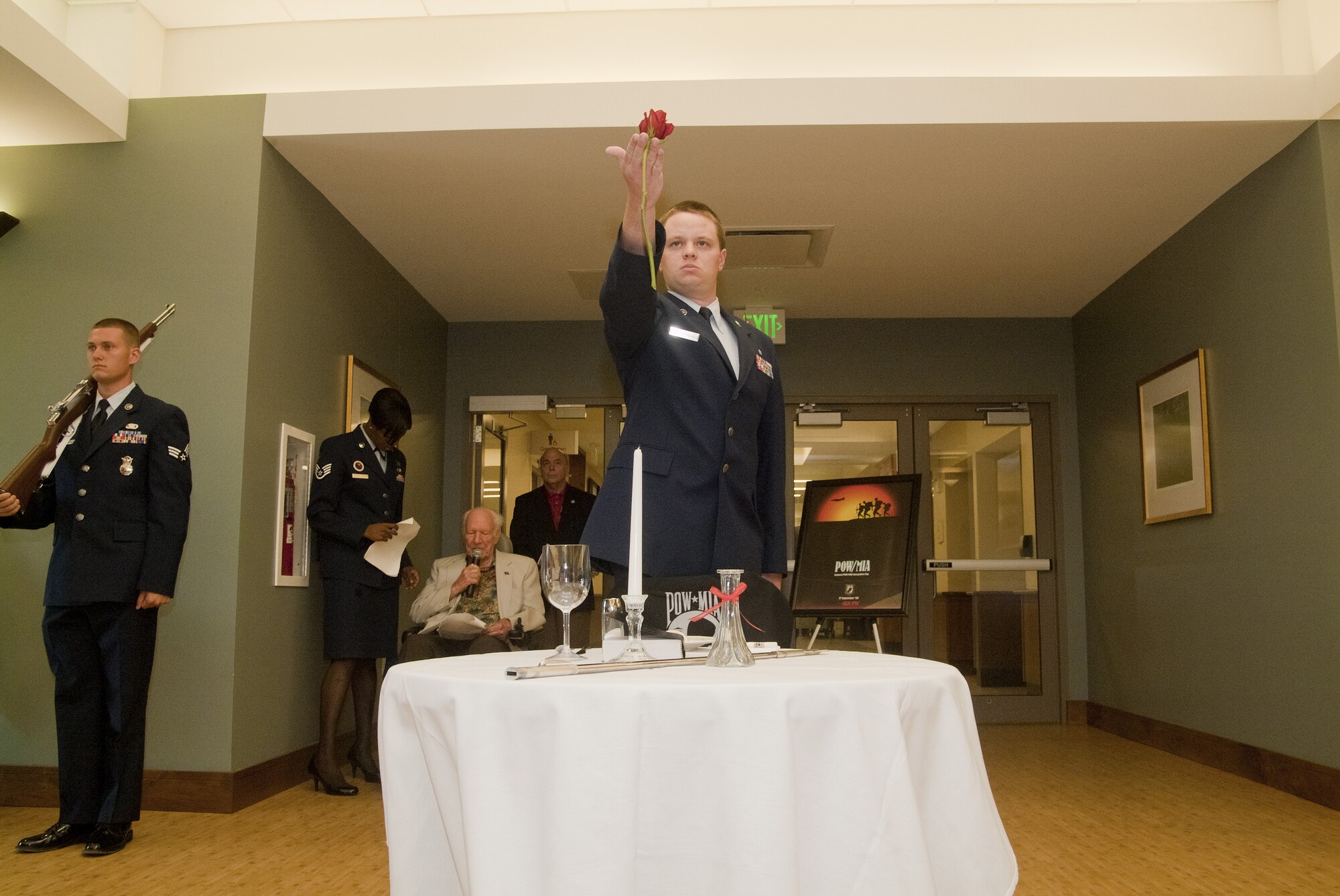 From left, Staff Sgt. Adrienne Russell George, Airman Leadership School instructor, and Wendell Ward wait as Senior Airmen Zachary Merryman, 81st Diagnostics and Therapeutics Squadron, places a rose on the POW/MIA table during a Memorial Day ceremony at the Armed Forces Retirement Home in Gulfport. Mr.Ward, an AFRH resident, was an Army corporal taken prisoner by the German army during World War
II who spoke at the ceremony.  (U.S. Air Force photo by Herb Welch)
