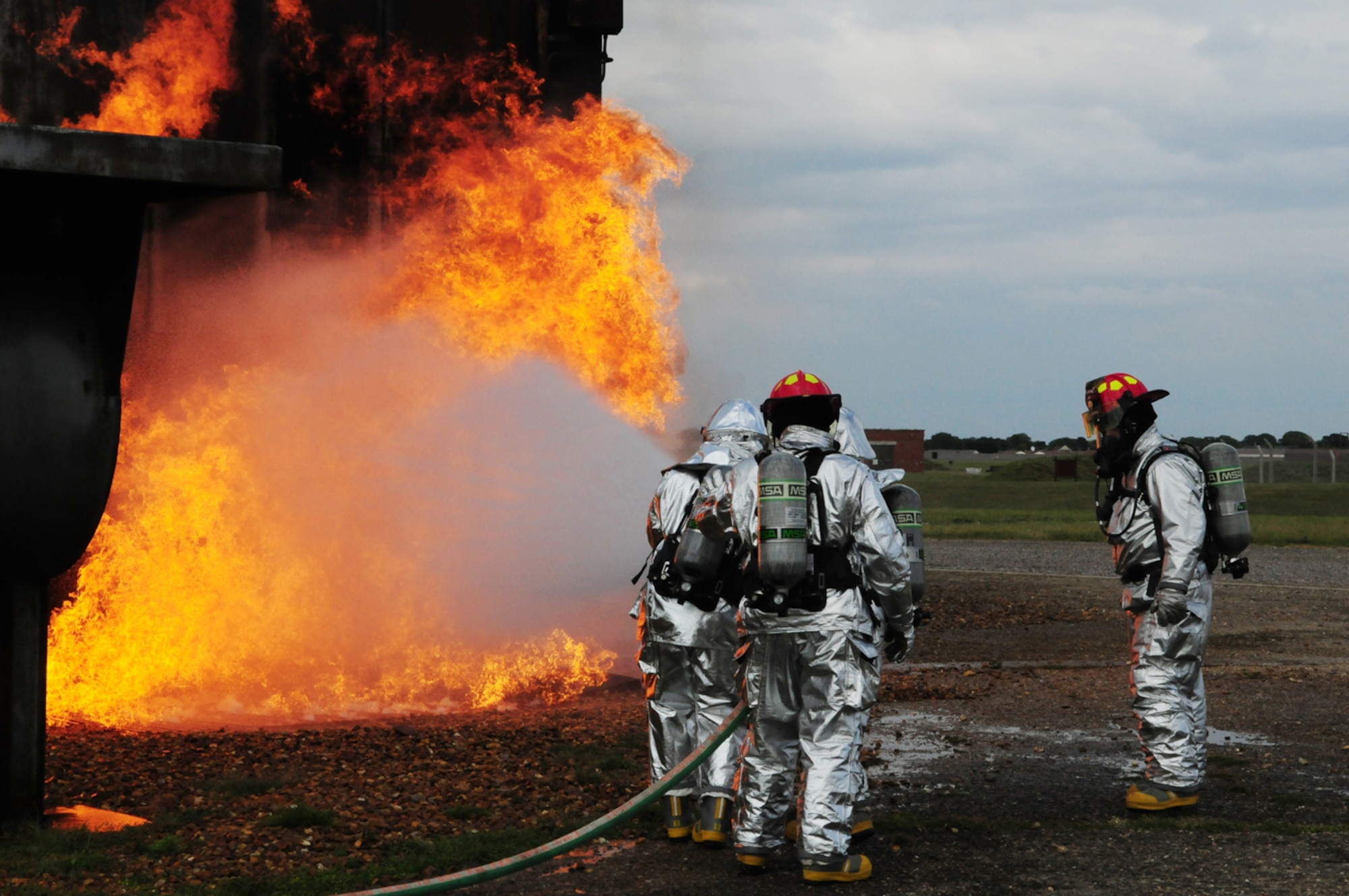 RAF MILDENHALL, England -- Cadet 2nd Class Craig Nowadly, left, a cadet with the U.S. Air Force Academy, Colo., along with firefighters Andy Hughes and Staff Sgt. Andy Booth, both 100th Civil Engineer Squadron Fire Department, train June 7, 2011, along with Col. Chad Manske, 100th Air Refueling Wing commander. The two men donned full protective gear and with the help of the firefighters, assisted in putting out the flames on the mock aircraft. They also had the chance to go into the smoke-filled fire training house with the firefighters, and search for a mannequin which they had to bring outside to safety. (U.S. Air Force photo/Karen Abeyasekere)