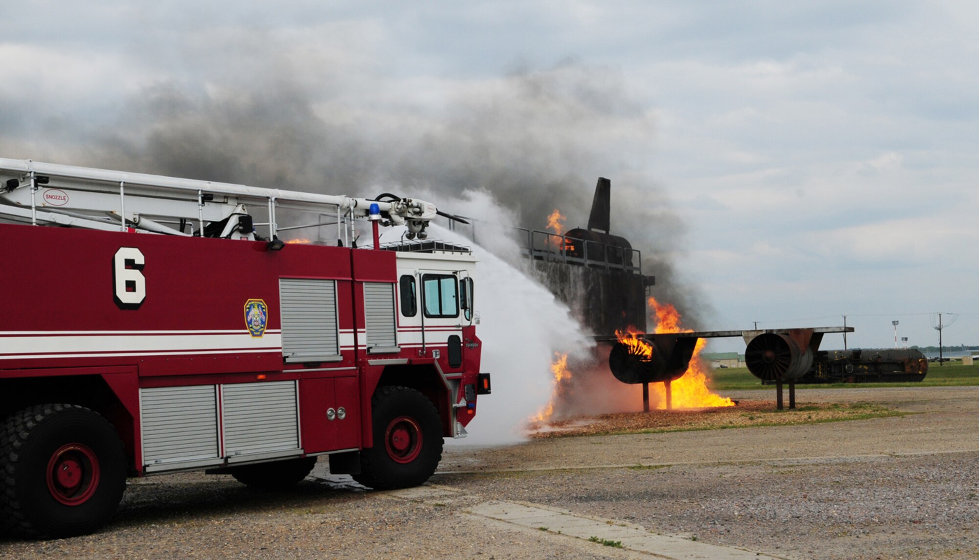 RAF MILDENHALL, England -- A fire truck, belonging to the 100th Civil Engineer Squadron Fire Department, does modulating training as it circles the live fire trainer and shoots water to put out the flames. Col. Chad Manske, 100th Air Refueling Wing commander, was on board the truck and spent time June 7, 2011, training with the firefighters. Also training alongside him was Cadet 2nd Class Craig Nowadly, a cadet from the U.S. Air Force Academy, Colo., who is spending a few weeks at RAF Mildenhall as part of his training. (U.S. Air Force photo/Karen Abeyasekere)