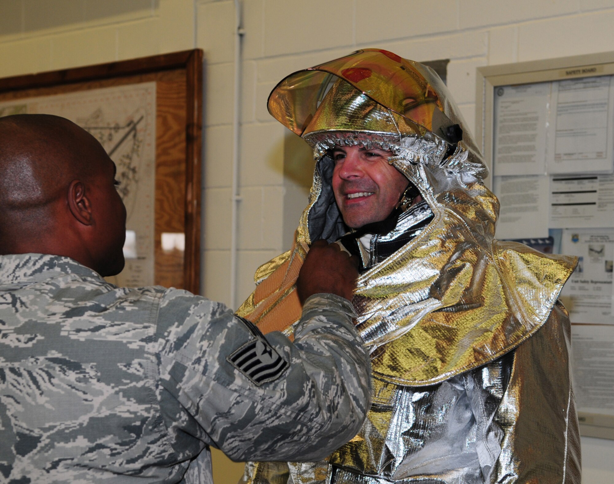 RAF MILDENHALL, England -- Tech. Sgt. Corey Coleman, 100th Civil Engineer Squadron Fire Department, adjusts the helmet and bunkers worn by Col. Chad Manske, 100th Air Refueling Wing commander, in preparation for live-fire training June 7, 2011. Colonel Manske had the opportunity to train with the firefighters before he leaves RAF Mildenhall later this month. (U.S. Air Force photo/Karen Abeyasekere)