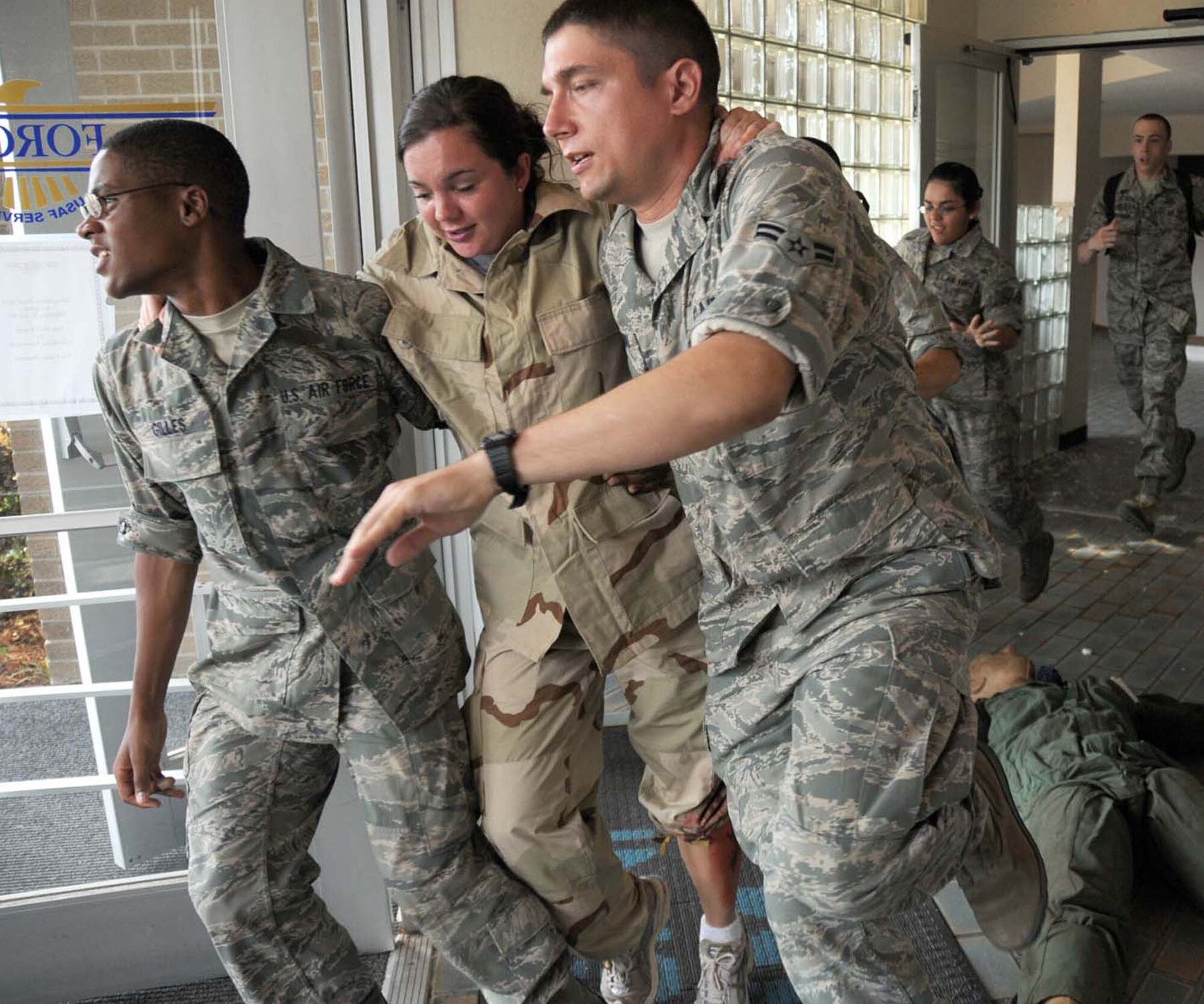 From left, Airman Basic Jahqui Gilles, Airman Katie Ewel and Airman 1st Class Alexander Tarnawski exit Muse Manor under the watchful eye of exercise evaluation team member Darrin McClure during an active shooter exercise, May 20, 2010. Airmen Gilles and Ewel were students in the 334th Training Squadron, and Airman Tarnawski was a student in the 336th TRS. Visitors to Keesler should expect delays at the gates and limited access to facilities June 21-22, particularly during the lockdown phase, as base emergency response teams conduct another active shooter exercise directed by Air Education and Training Command.  (U.S. Air Force photo by Kemberly Groue)