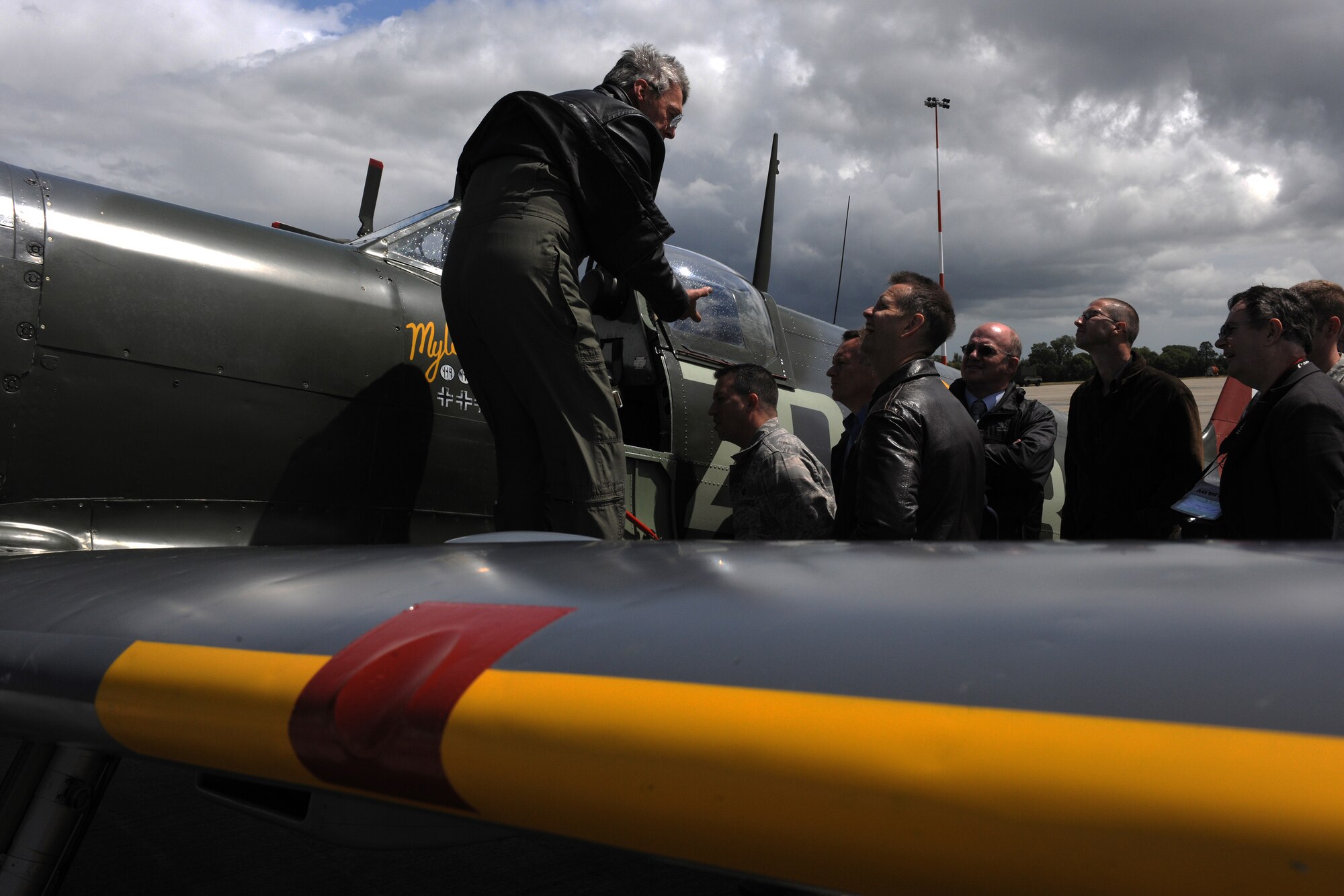 Alistair Kay explains the Spitfire Mk9 to Col. Brian Kelly, 501st Combat Support Wing commander, and Col. Jeffrey Renner, 422nd Air Base Group commander, and gathered media representatives during the Royal International Air Tattoo Media Day at RAF Fairford June 8. (U.S. Air Force photo/1st Lt. Brian Maguire)