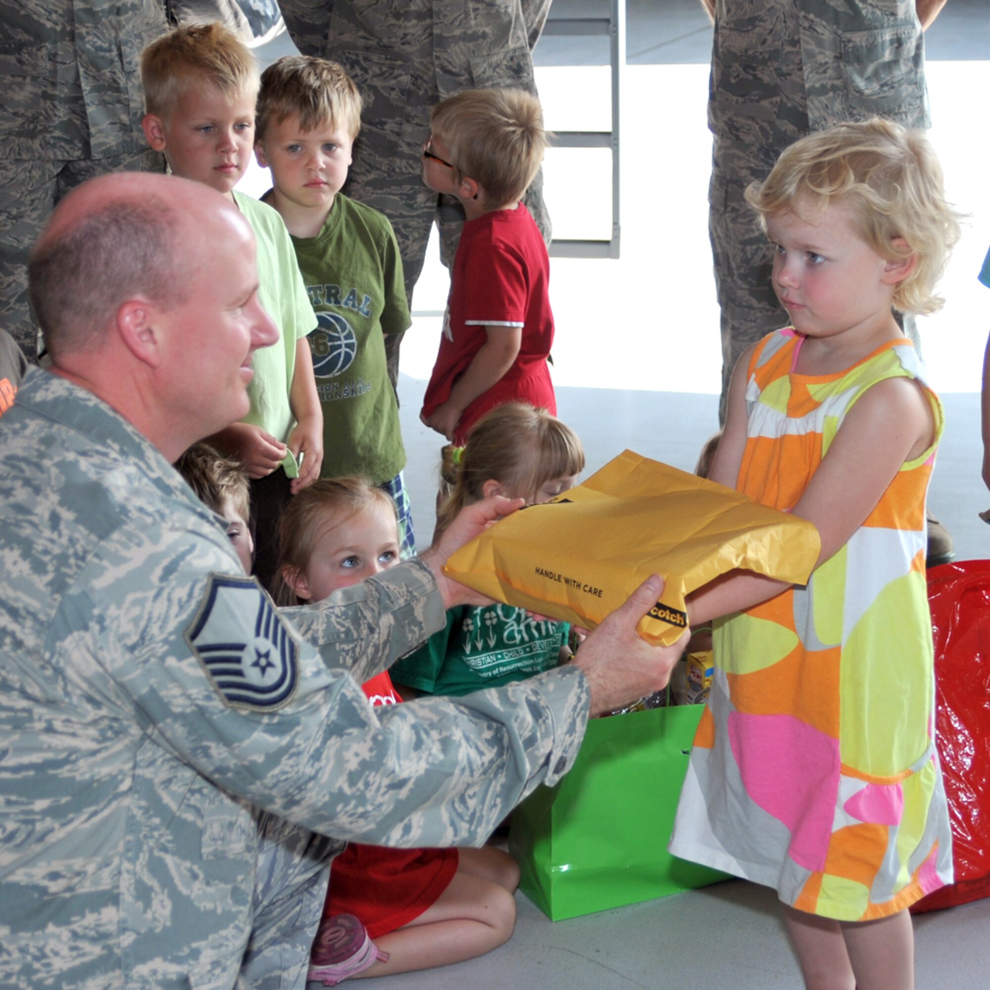 Master Sgt. Thomas Mitchell, 114th Maintenance Squadron, recieves a care package from Rowan Alberts at Joe Foss Field, S.D. June 7.  Rowan and other children from the Open Arms Christian Child Center visited the base to distribute care packages they put together for deployed members. (Air Force photo by Master Sgt. Nancy Ausland)(RELEASED)