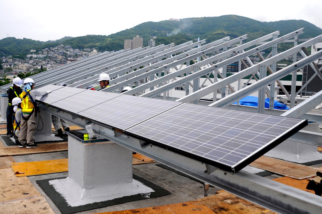 Japanese contractors install solar panels on the Public Works building roof at Fleet Activities Sasebo, Japan, part of a $564,000 project to improve energy efficiency on base. This marks the first time solar panels have been used on the base.
