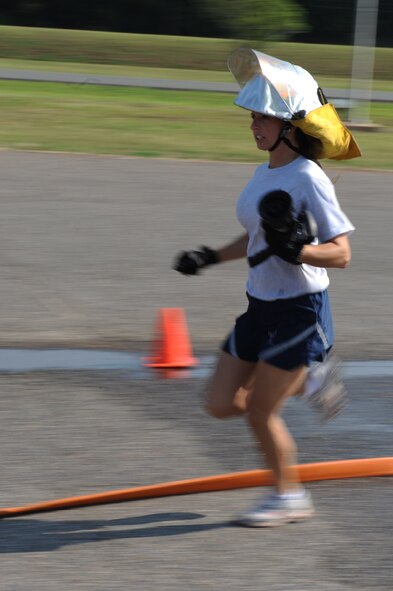 An Airman from the 2nd Civil Engineer Squadron runs while holding a fire-hose nozzle during the hose connection relay for the third annual Fire Muster on Barksdale Air Force Base, La., June 10. Four Airmen from each squadron must unravel fire hoses, connect them to the truck, give the signal to turn the water on and knock down a traffic cone with a stream of water. (U.S. Air Force photo/Airman 1st Class Micaiah Anthony)(RELEASED)