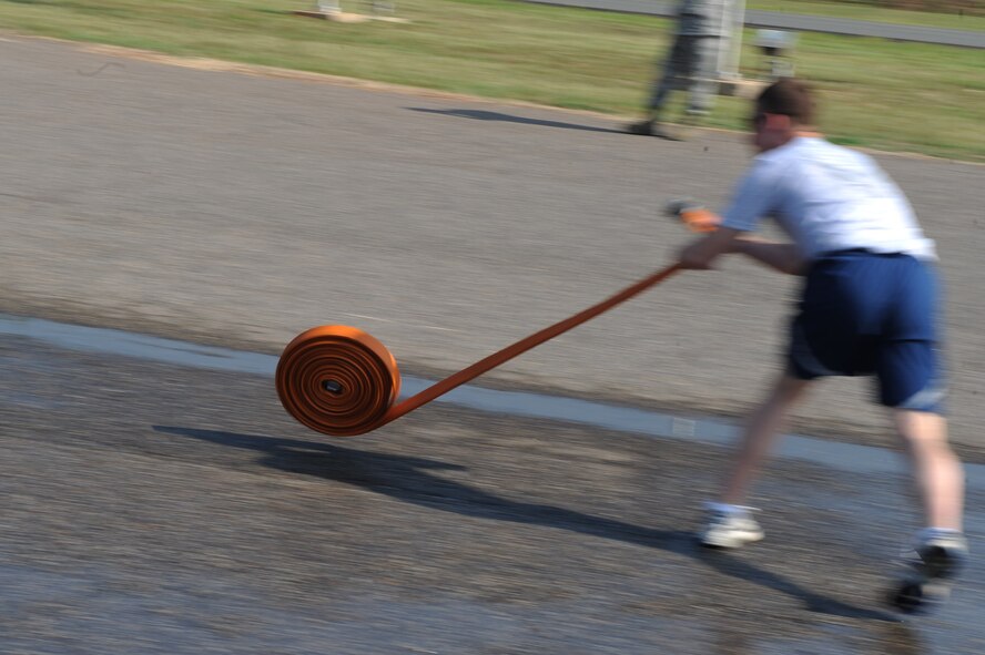 An Airman from the 2nd Civil Engineer Squadron unravels a fire-hose during the hose connection relay for the third annual Fire Muster on Barksdale Air Force Base, La., June 10. Four Airmen from each squadron must unravel fire hoses, connect them to the truck, give the signal to turn the water on and knock down a traffic cone with a stream of water. (U.S. Air Force photo/Airman 1st Class Micaiah Anthony)(RELEASED