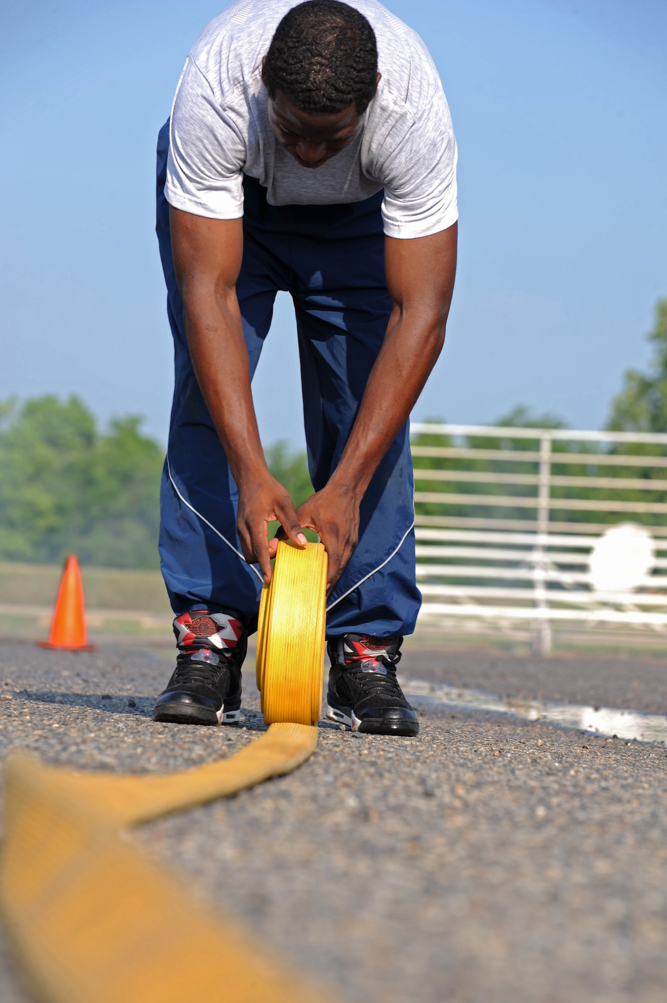 An Airman from the 2nd Force Support Squadron rolls up a fire hose after the hose connection relay during the third annual Fire Muster on Barksdale Air Force Base, La., June 10. Four Airmen from each squadron must unravel fire hoses, connect them to the truck, give the signal to turn the water on and knock down a traffic cone with a stream of water. (U.S. Air Force photo/Airman 1st Class Micaiah Anthony)(RELEASED)
