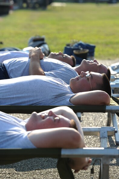 Airmen from the 2nd Communications Squadron lay in cots for the midnight alarm event during the third annual Fire Muster on Barksdale Air Force Base, La., June 10. The midnight alarm event simulates lying in bed at night when the alarm goes off. Participants have to get out of their cots and don the full firefighter ensemble. By regulation, firefighters have 60 seconds to be completely dressed and headed out of the station. (U.S. Air Force photo/Airman 1st Class Micaiah Anthony)(RELEASED)