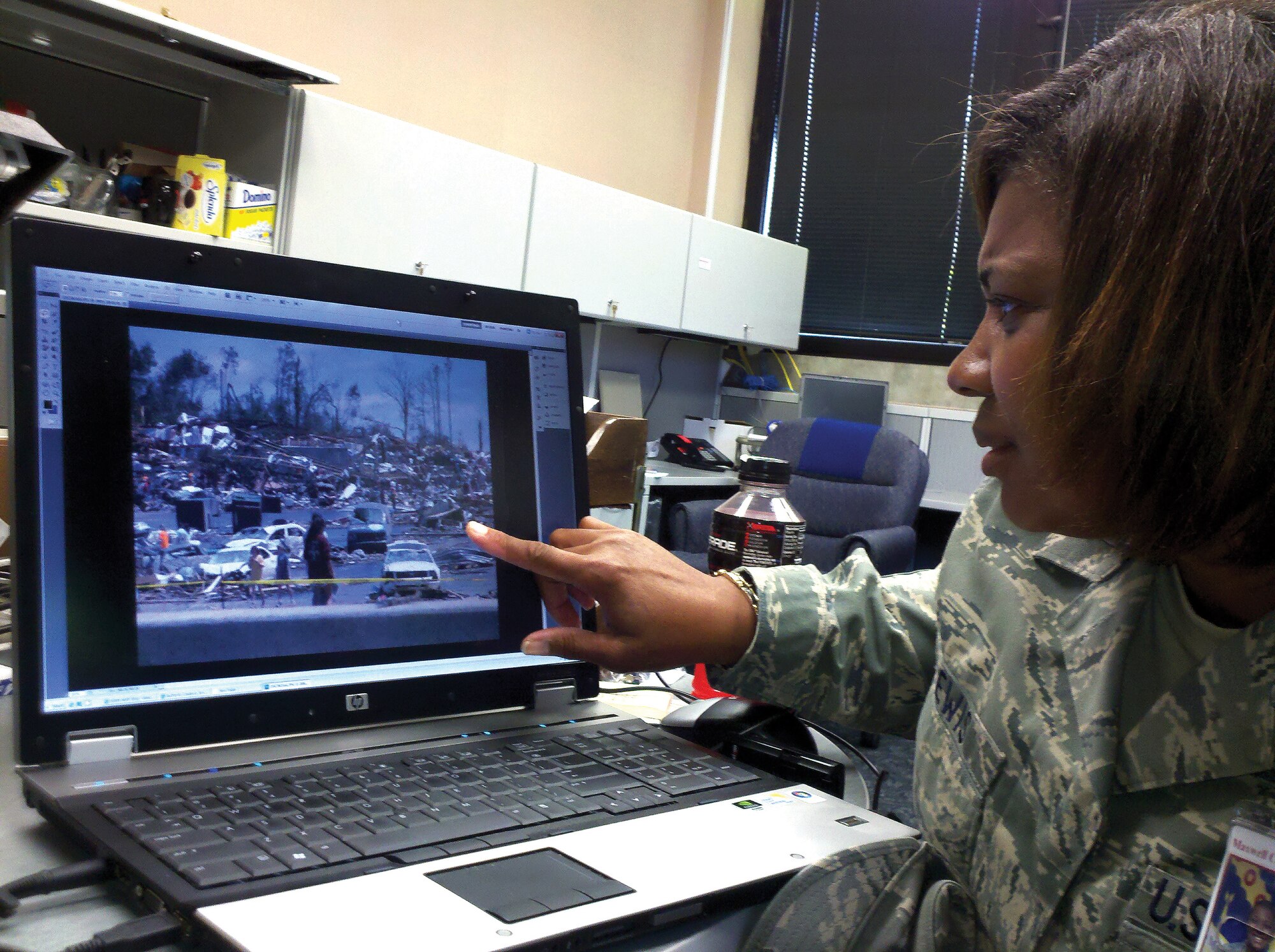 Above, Maj. Cynthia Lewis of the 908th ASTS examines one of her photos of the devastation caused by the April 27 tornado in Tuscaloosa. (Air Force photo by Gene H. Hughes)