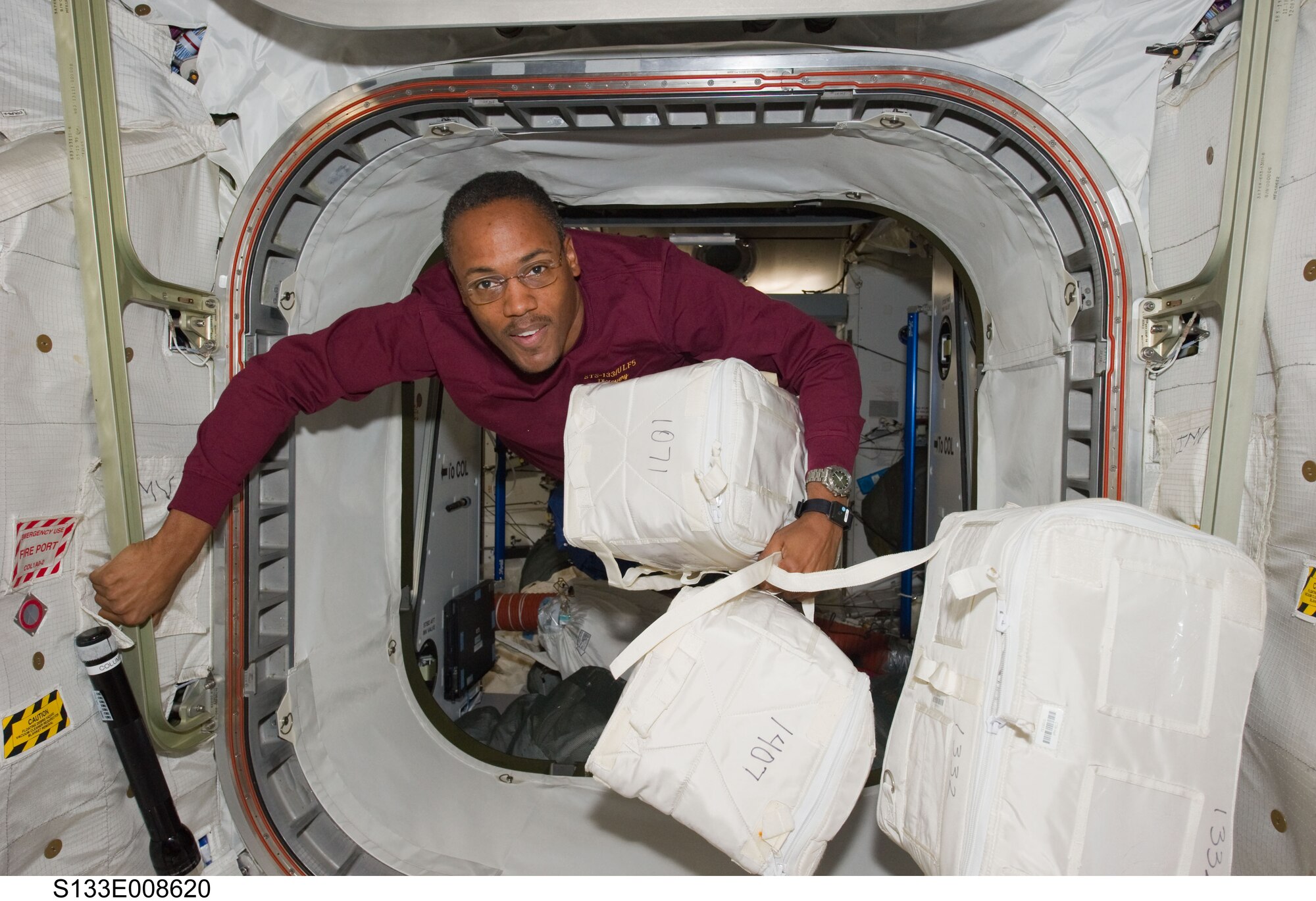 Col. Alvin Drew moves stowage containers through a hatch on the International Space Station while space shuttle Discovery remains docked with the station in March. (Courtesy photo)