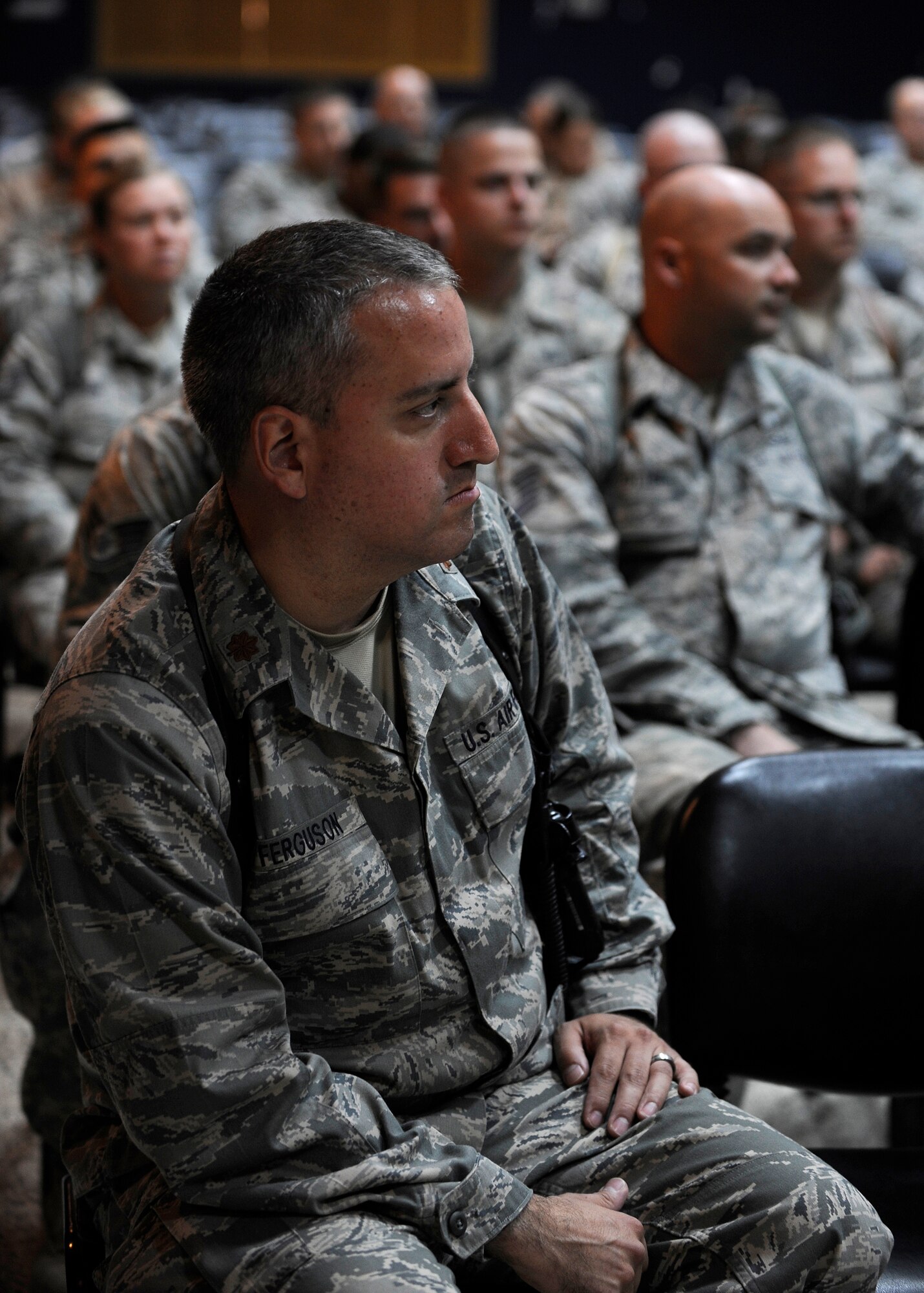 CAMP TAJI, Iraq -- Maj. James Ferguson, 821st Expeditionary Training Squadron director of operations, listens to Brig. Gen. Anthony Rock, Iraq Training and Advisory Mission - Air director, talk about the road ahead for advisors during a commander's call at the base's theater June 8. More than 30 advisors and instructors from the 821st ETRS help educate and train Iraqis at the Iraqi Air Force Training School on instructional techniques, curriculum development and English language application. Major Ferguson is deployed from Air Force ROTC Det. 215 at Indiana University in Bloomington, Ind., and calls Inchelium, Wash., his hometown.  (U.S. Air Force/Tech. Sgt. Jason Lake)