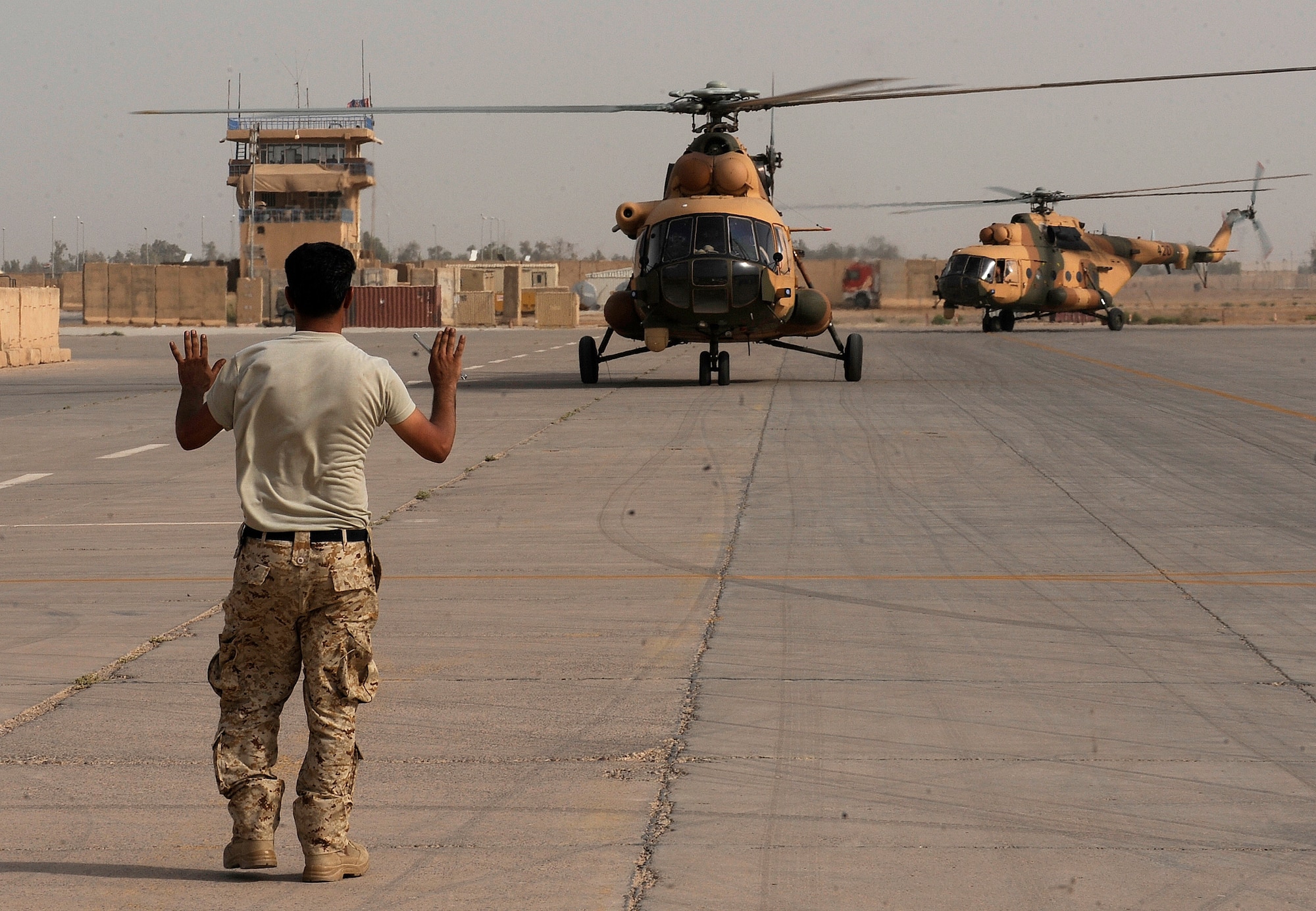 CAMP TAJI, Iraq -- An Iraqi Army Aviation Command soldier marshals in two new Mi-171E helicopters as they arrive June 8. With the help of Iraq Training and Advisory Mission - Air and Iraq Security Assistance Mission advisors, IqAAC officials purchased 22 of the aircraft from Europe last year for more than $150 million. The last two Mi-171 helicopters of the order are expected to be delivered by the end of this month. (U.S. Air Force/Tech. Sgt. Jason Lake)
