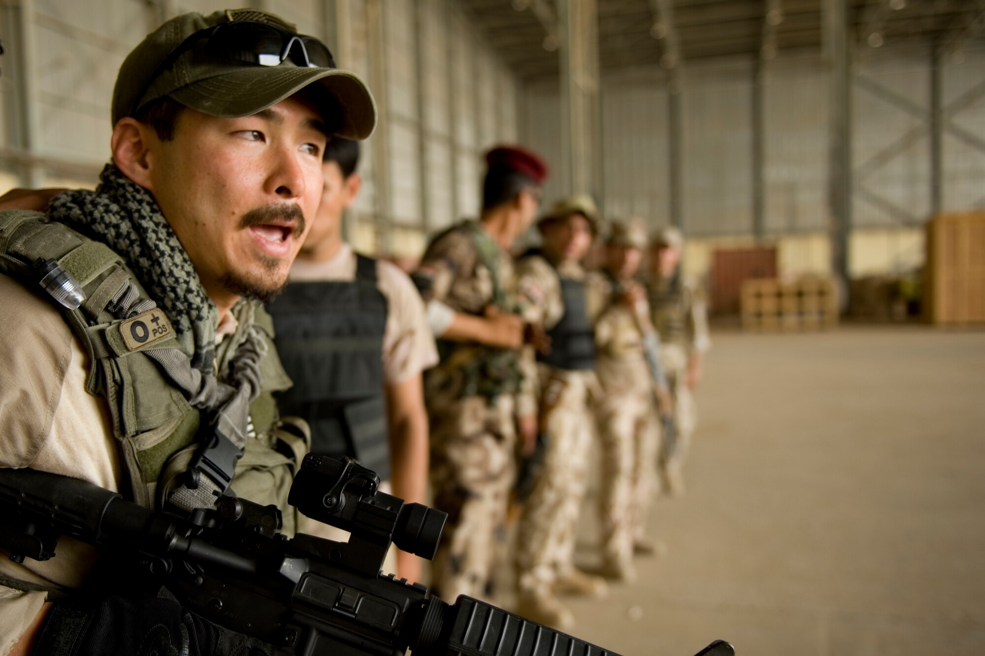Special Agent Masashi Yamazaki (left), instructs Iraqi security forces members on personal security operations at New Al Muthana Air Base, Iraq, June 1. The Iraqis were participating in personal security operations training to develop the skills needed to protect their leaders in future operations. (U.S. Air Force photo/Staff Sgt. Levi Riendeau)