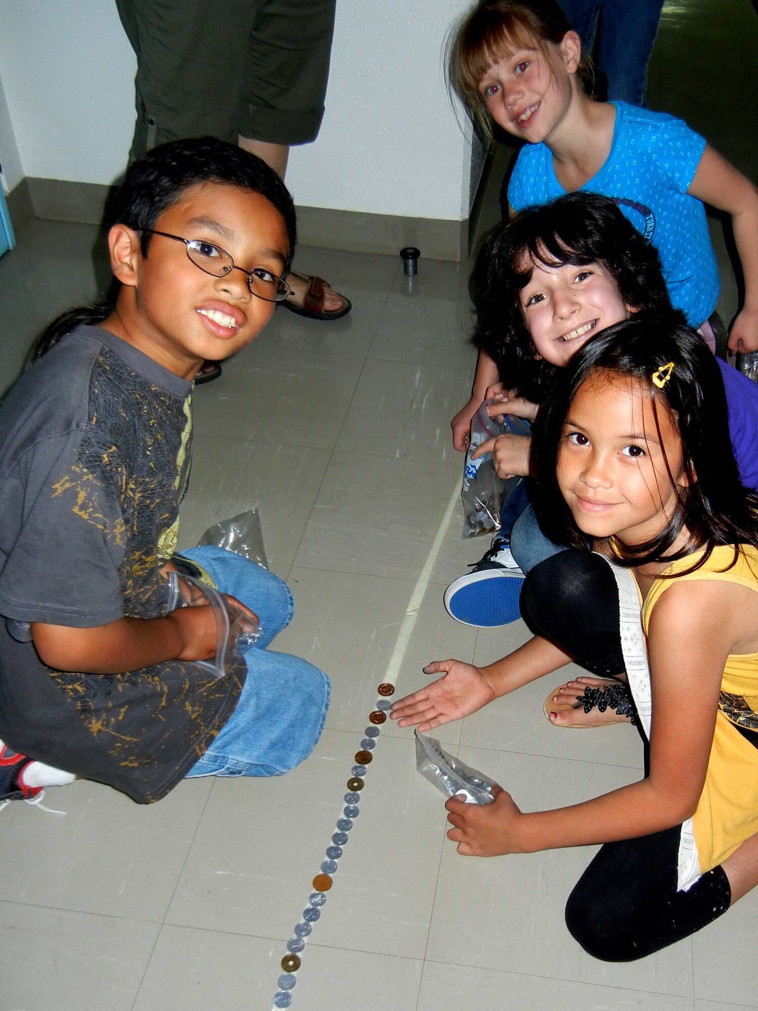 MISAWA AIR BASE, Japan -- Jeremiah Ardon (left), Helen McCammond, Jett Magaña, and Avery Eschliman (right, front to back), third-grade students at Sollars Elementary School, place Japanese Yen in a line that wraps throughout the school June 8.  The line measured a distance of 968 feet, or approximately three football fields, and totaled ¥120,270 Yen, or about $1,500.  The donations were given to the Japanese Red Cross to help with the Tsunami Relief Fund.  (Photo by Mrs. Florrie Anest)