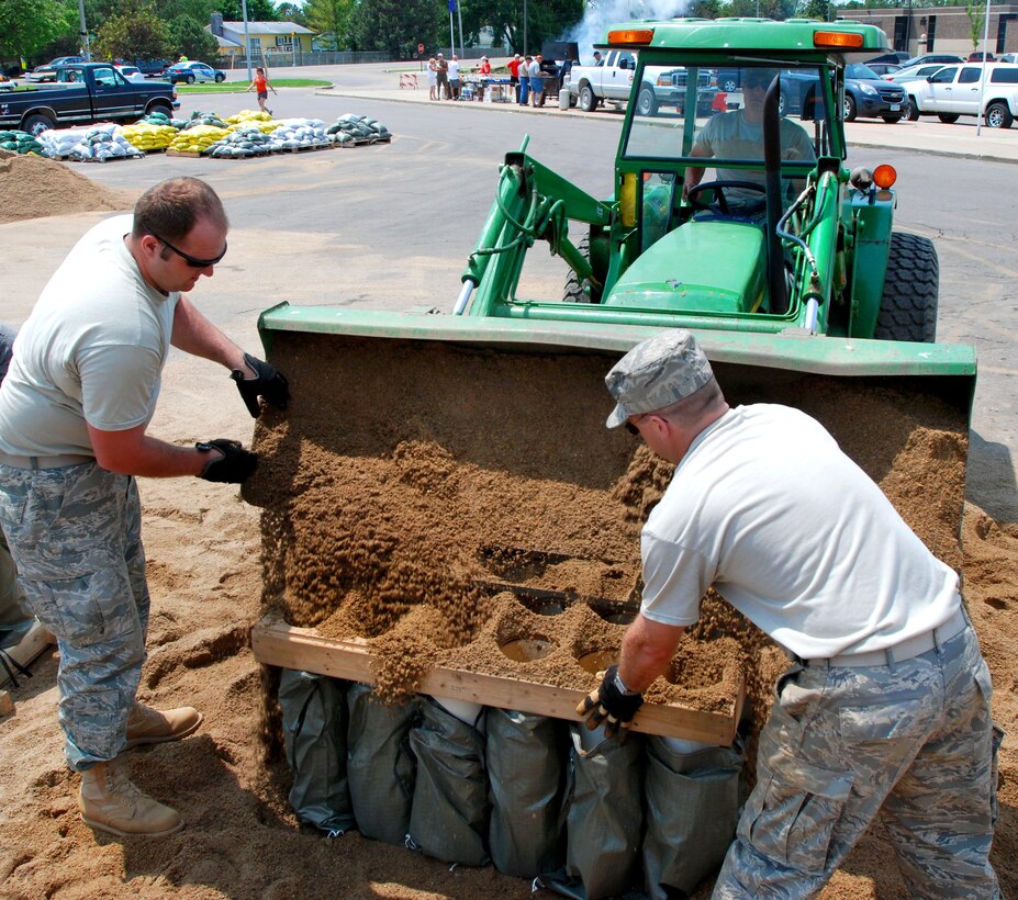 Air Force Tech. Sgts. Derek Frerich, left, and Andy Anderson help unload sand into sandbags at the Dakota Valley High School in Dakota Dunes, S.D., June 5, 2011. Frerich and Anderson are assigned to the assigned to the 114th Fighter Wing of the South Dakota Air National Guard. 