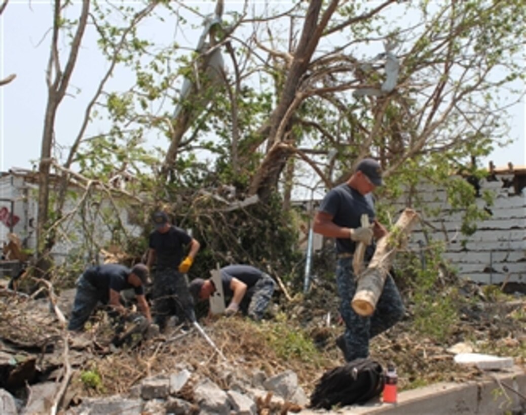 Petty Officer 2nd Class Pat Patterson (left), Lt. j.g. Joe Innerst, Petty Officer 2nd Class Travis Fitzgerald and Lt. Ryan Sullivan clear debris from a backyard in Joplin, Mo., on June 7, 2011.  Eight sailors assigned to the fast attack submarine USS Missouri (SSN 780) are helping with clean-up efforts in Joplin.  