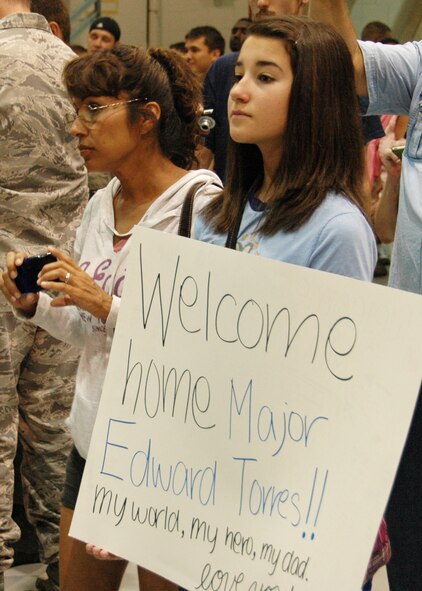 Inside a Hurlburt Field hangar, Erica Torres holds a sign as she looks for her father, Maj. Ed Torres, 919th Maintenance Group,as he and dozens of fellow Duke Field reservists returned home June 8 from a wartime deployment.    Hundreds of family and military members from Duke and Hurlburt Fields were on hand for the Operation Homecoming event.   (U.S. Air Force photo/Dan Neely)