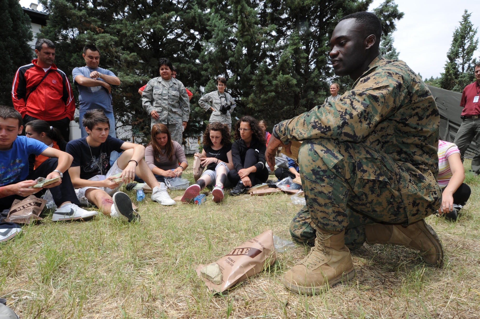 CAMP PEPELISHTE, Macedonia -- U.S. Marine Staff Sgt. Tresor Mbunker, 4th Logistics Group, Personnel Retrieval Process Company mortuary affairs staff NCO in charge, demonstrates how to cook and use the items found in a Meal, Ready to Eat to local Macedonian students who volunteered to be "victims" of a simulated car accident or building and bridge collapse as part of a medical emergency response exercises during Medical Training Exercise in Central and Eastern Europe 2011 June 11.  Macedonian students and U.S. service members were moulaged to make the exercises more realistic. The countries participating in this year's MEDCEUR are Macedonia, Montenegro, Bosnia and Herzegovina, Serbia, Slovenia and Norway.  MEDCEUR is a Partnership for Peace and Chairman of the Joint Chiefs of Staff-sponsored regional and multilateral exercise in Central and Eastern Europe designed to provide medical training and operational experience in a deployed environment.  (U.S. Air Force photo/Staff Sgt. Nadine Y. Barclay)