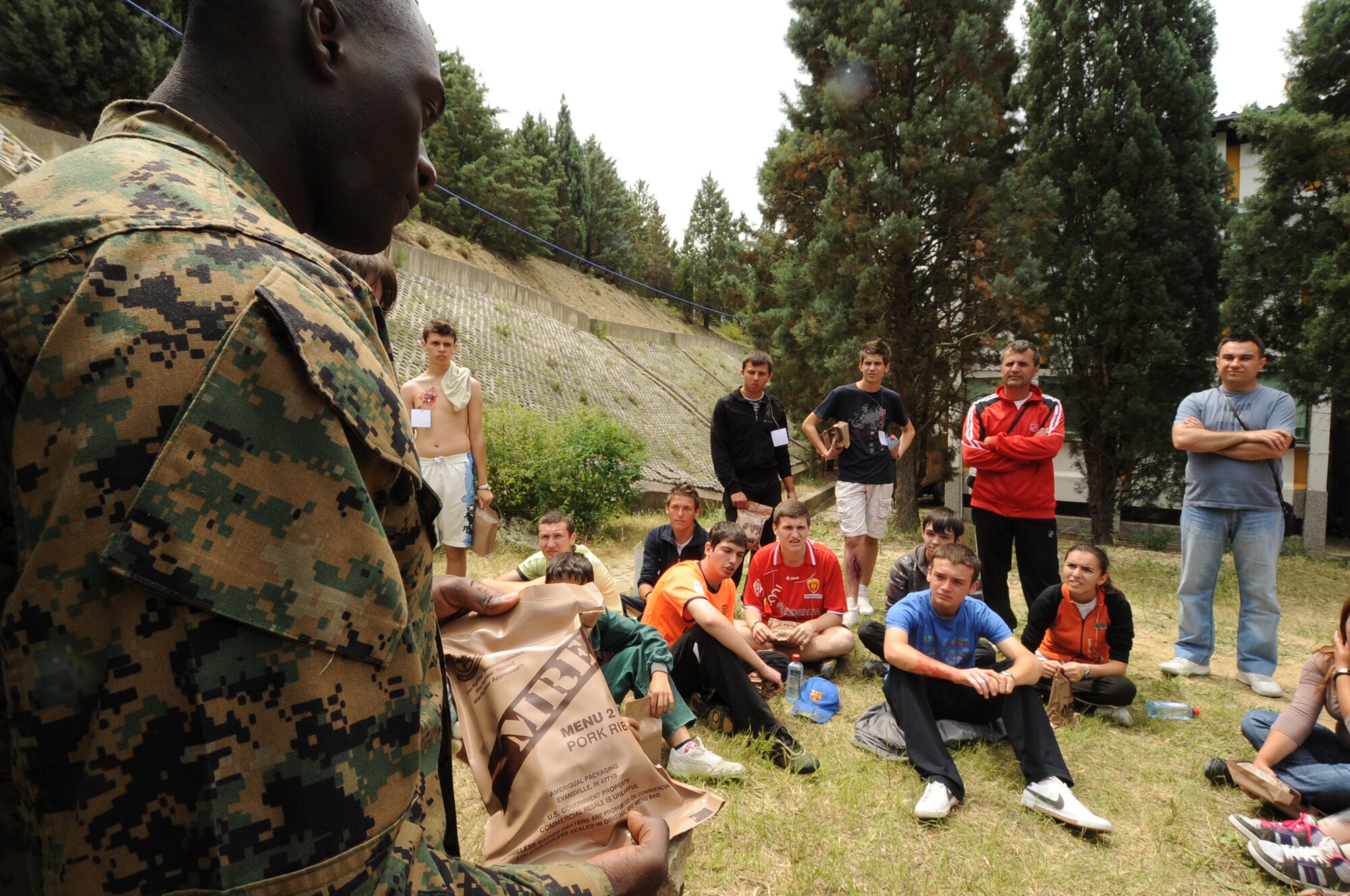 CAMP PEPELISHTE, Macedonia -- U.S. Marine Staff Sgt. Tresor Mbunker, 4th Logistics Group, Personnel Retrieval Process Company mortuary affairs staff NCO in charge, demonstrates how to cook and use the items found in a Meal, Ready to Eat to local Macedonian students who volunteered to be "victims" of a simulated car accident or building and bridge collapse as part of a medical emergency response exercises during Medical Training Exercise in Central and Eastern Europe 2011 June 11.  Macedonian students and U.S. service members were moulaged to make the exercises more realistic. The countries participating in this year's MEDCEUR are Macedonia, Montenegro, Bosnia and Herzegovina, Serbia, Slovenia and Norway.  MEDCEUR is a Partnership for Peace and Chairman of the Joint Chiefs of Staff-sponsored regional and multilateral exercise in Central and Eastern Europe designed to provide medical training and operational experience in a deployed environment.  (U.S. Air Force photo/Staff Sgt. Nadine Y. Barclay)