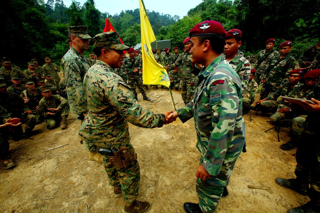 Capt. Rudy Cazares, the Landing Force Company Commander, shakes hands with Maj. Farriz Bin Ahmad Rlawawi, the Company Commander of Company C, 8th Royal Ranger Regiment, Malaysian Army.  The two officers exchanged gifts during a closing ceremony June 13, concluding the Malaysian portion of Cooperation Afloat Readiness and Training (CARAT) 2011. CARAT is an annual series of bilateral exercises held between the U.S. and Southeast Asian nations with the goals of enhancing regional cooperation, promoting mutual trust and understanding, and increasing operational readiness throughout the participating nations.  While in Malaysia, U.S. and Malaysian service members trained together on jungle, urban and amphibious operations.