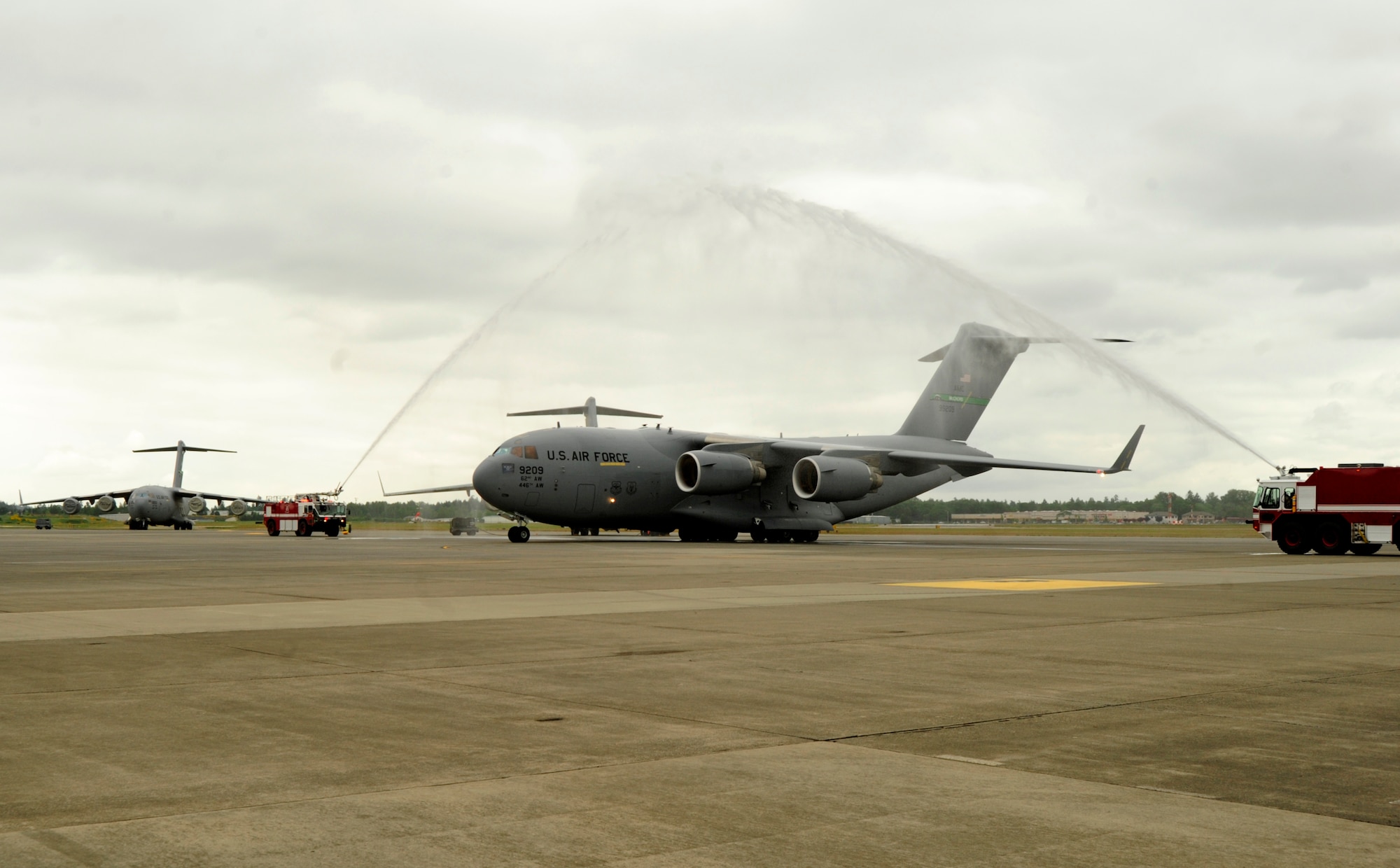 A C-17 Globemaster III, operated by Col. Kevin Kilb, 62nd Airlift Wing commander, is showered by fire trucks after the colonel’s final flight at Joint Base Lewis-McChord June 8. (U.S. Air Force photo/Adamarie Lewis-Page)