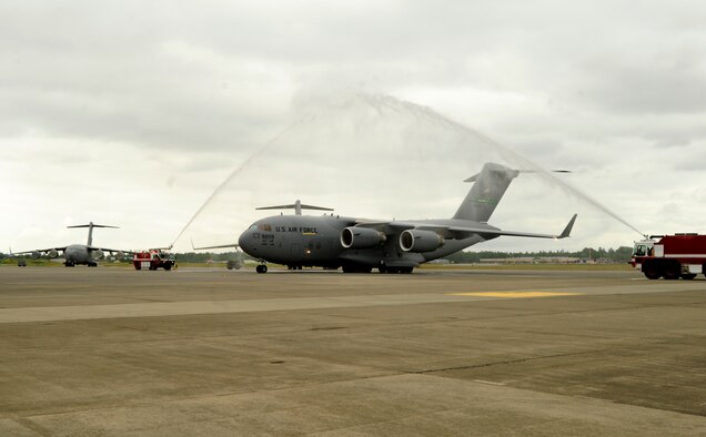 A C-17 Globemaster III, operated by Col. Kevin Kilb, 62nd Airlift Wing commander, is showered by fire trucks after the colonel’s final flight at Joint Base Lewis-McChord June 8. (U.S. Air Force photo/Adamarie Lewis-Page)