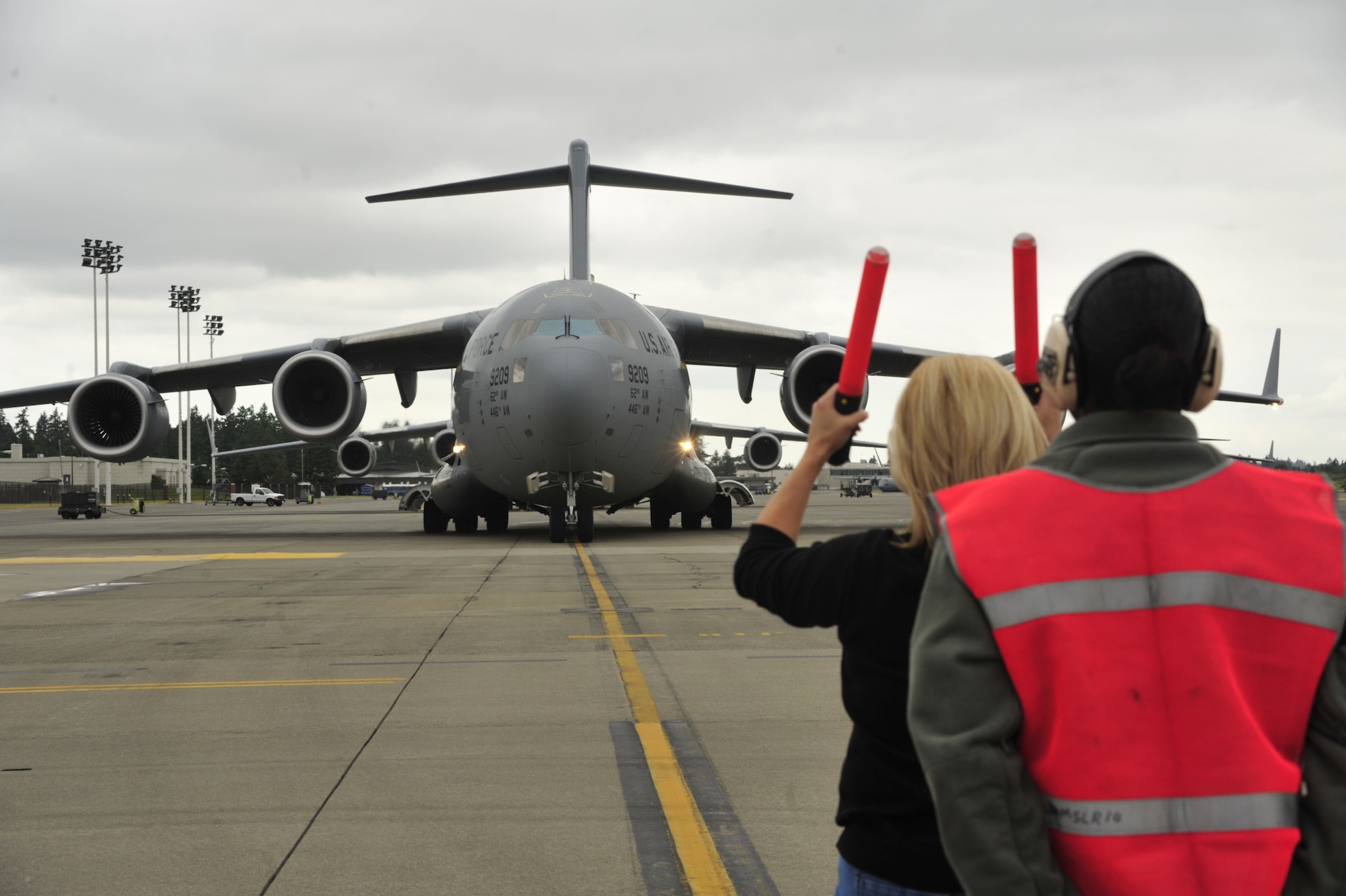 Stacey Kilb, wife of Col. Kevin Kilb, 62nd Airlift Wing commander, is assisted by Tech. Sgt. Tara Jackson, 62nd Aircraft Maintenance Squadron maintenance technician, as she marshals in her husband at Joint Base Lewis-McChord June 8. This was Colonel Kilb’s final flight. (U.S. Air Force photo/Staff Sgt. Frances Kriss)