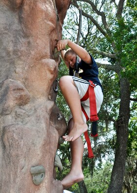 A young boy gives the climbing wall a try at the Team Eglin Picnic at Post’l Point June 10.  Eglin personnel and their families enjoyed an afternoon complete with food, beverages and activities, including a water slide, bouncy house, climbing wall, face painting and horseback riding. (U.S. Air Force photo/Kevin Gaddie)
