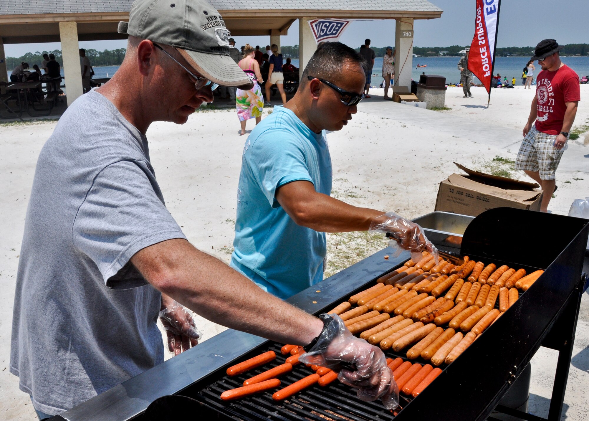 Volunteers grill up hot dogs for hungry patrons at the Team Eglin Picnic at Post’l Point June 10.  Eglin personnel and their families enjoyed an afternoon complete with food, beverages and activities, including a water slide, bouncy house, climbing wall, face painting and horseback riding. (U.S. Air Force photo/Kevin Gaddie) 
