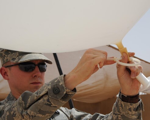 U.S. Air Force Staff Sgt. Casey Fletcher, 532nd Expeditionary Operations Support Squadron meteorologist, ties the radiosonde to the weather balloon before launching it at Al Asad Air Base, Iraq, May 28. The radiosonde travels up with the weather balloon to transmit data back to a computer telling the wind speed, atmospheric pressure, temperature and humidity. 