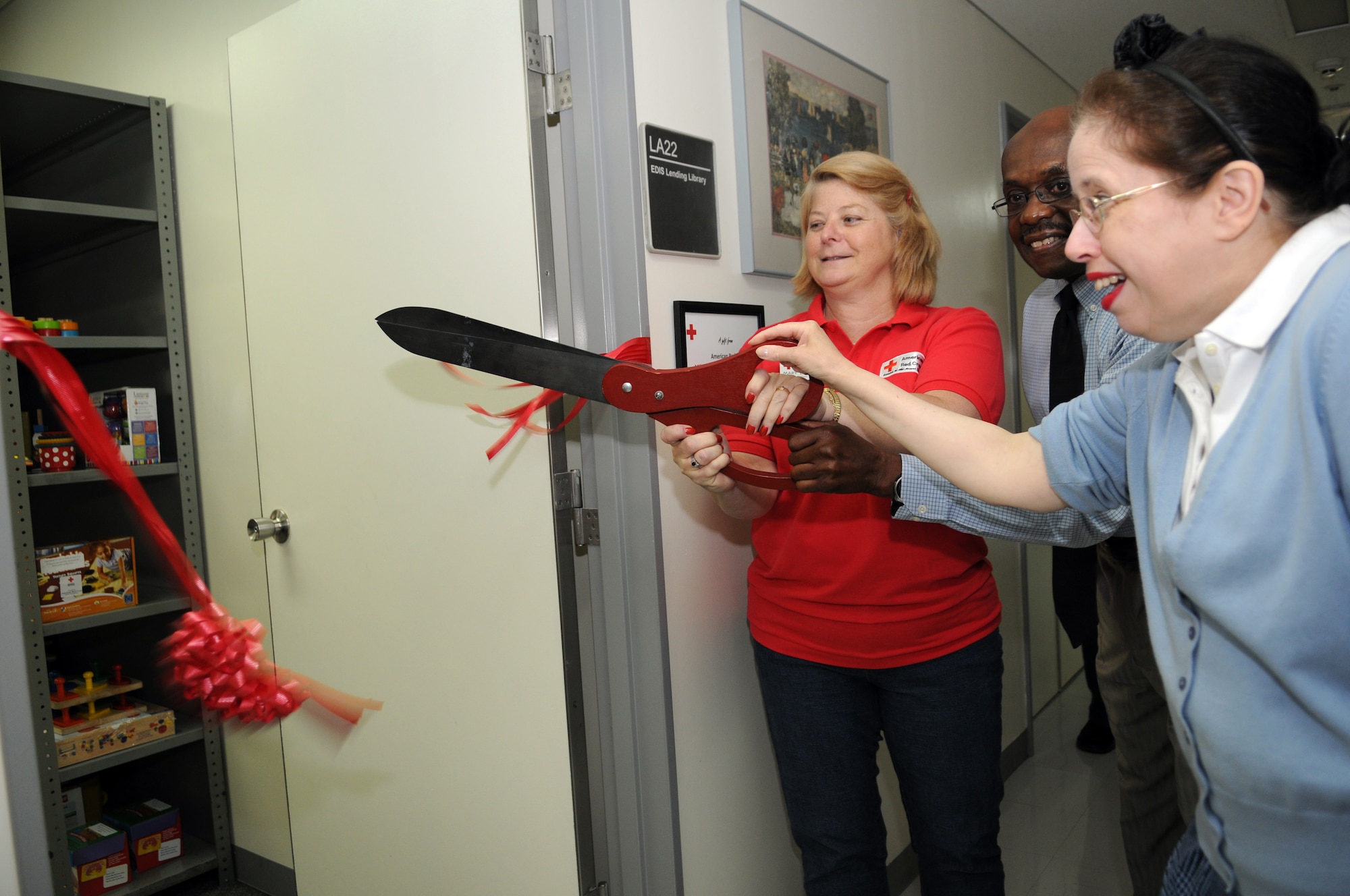 YOKOTA AIR BASE, Japan -- Event attendees and American Red Cross members cut the ribbon at the Educational and Developmental Intervention Services lending library grand opening at Yokota Air Base, Japan, June 10, 2011. The lending library provides parentsof special needs children with developmental toys, children books and educational resources. (U.S. Air Force photo/Airman 1st Class Krystal M. Garrett)