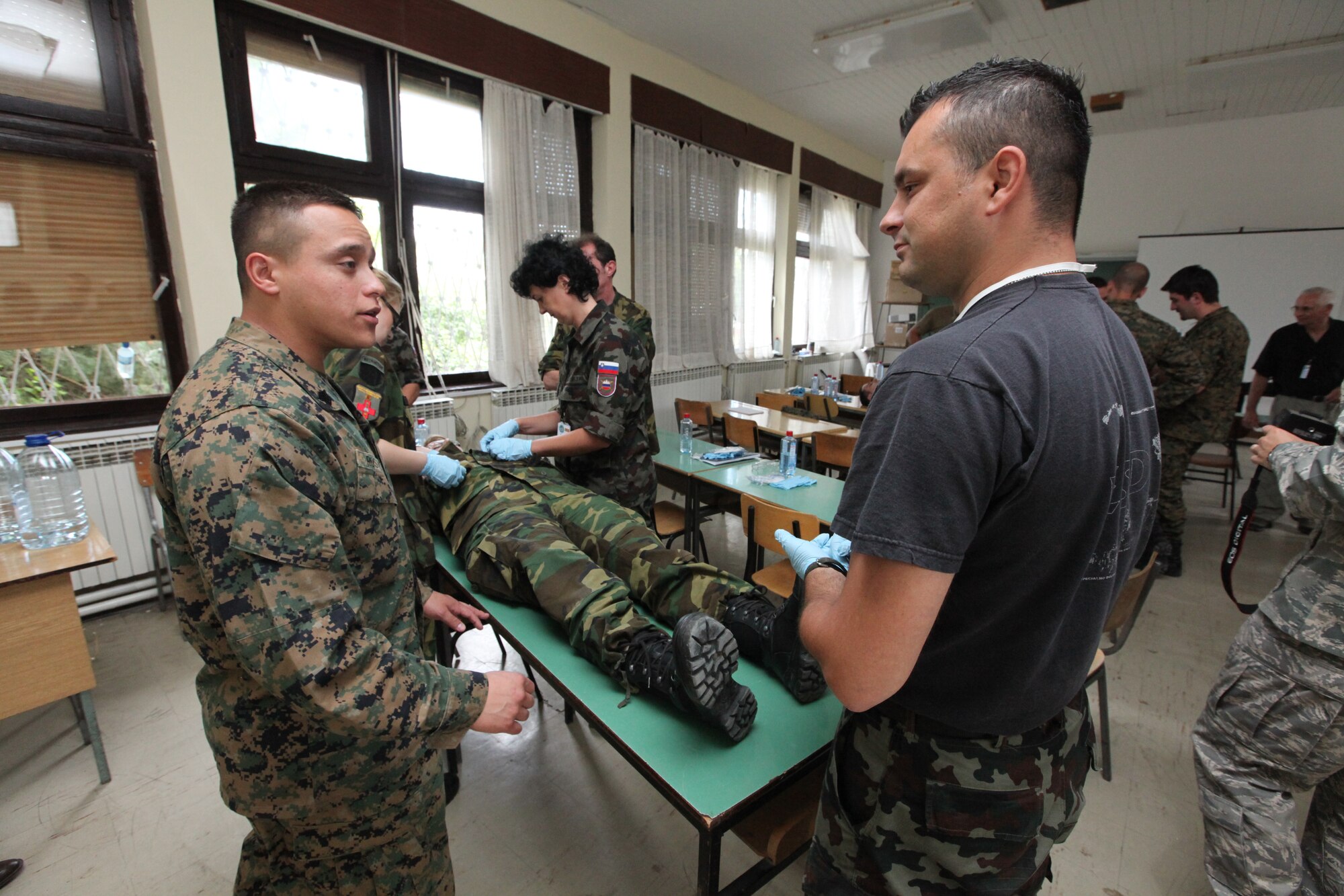 CAMP PEPELISHTE, Macedonia – Sgt. Sergio Rosas, a Personnel and Retrieval Processing specialist, answers questions asked by a Slovenian service member as other multinational students work together during the practical application portion on the mortuary affairs class led by U.S. Marines from Personnel and Retrieval Processing Company, 4th Marine Logistics Group, out of Smyrna, Ga., and Anacostia, Washington, D.C., here June 10.  This brief was to teach multinational partners on how the Marine Corps processes human remains and conducts search and recovery missions.  The Marines came to Macedonia for Medical Training Exercise in Central and Eastern Europe 2011 to teach foreign military services how to conduct mortuary affairs. MEDCEUR is an annual Chairman of the Joint Chiefs of Staff-sponsored regional and multilateral exercise and is designed to provide medical training and operational experience in a deployed environment for U.S. and partner nations. The countries participating in this year’s MEDCEUR are Macedonia, Montenegro, Bosnia and Herzegovina, Serbia, Slovenia and Norway.  The exercise will include both classroom and hands-on training and run until June 15.