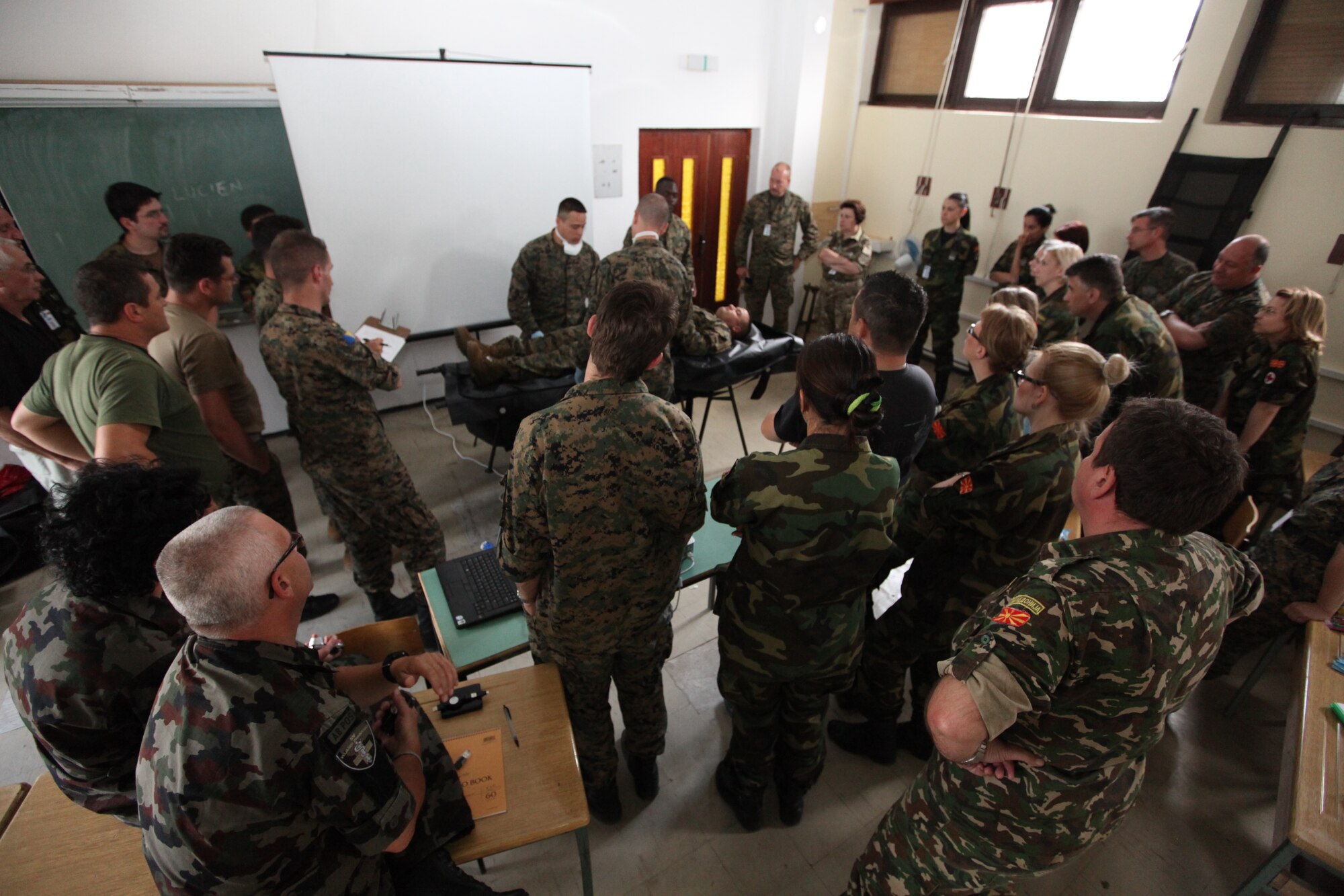 CAMP PEPELISHTE, Macedonia – Students at the mortuary affairs class given by the U.S. Marine Corps crowd around a demonstration led by Marines from Personnel and Retrieval Processing Company, 4th Marine Logistics Group, out of Smyrna, Ga., and Anacostia, Washington, D.C., here June 10.  This brief taught multinational partners how the Marine Corps processes human remains and conducts search and recovery missions.  The Marines came to Macedonia for Medical Training Exercise in Central and Eastern Europe 2011 to teach multinational partners from seven countries how to conduct mortuary affairs. MEDCEUR is an annual Chairman of the Joint Chiefs of Staff-sponsored regional and multilateral exercise and is designed to provide medical training and operational experience in a deployed environment for U.S. and partner nations. The countries participating in this year’s MEDCEUR are Macedonia, Montenegro, Bosnia and Herzegovina, Serbia, Slovenia and Norway.  The exercise will include both classroom and hands-on training and run until June 15.
