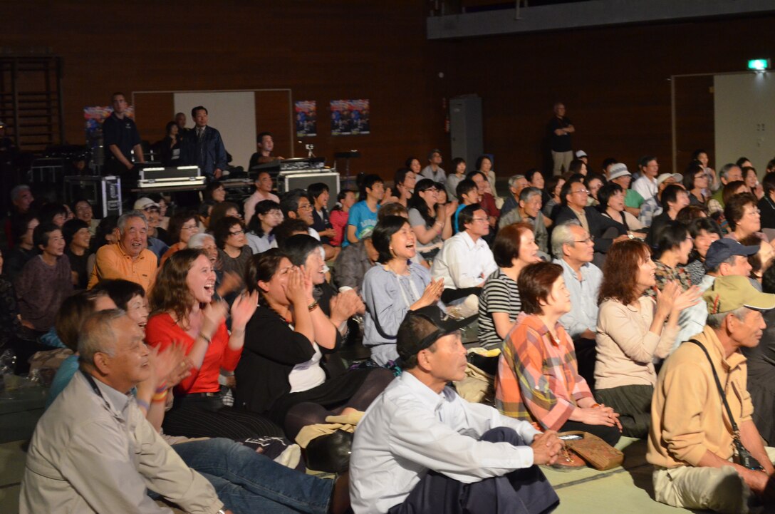 Japanese audience claps along with Pacific Trends sitting on Tatami Mats.   People were bused to the gymnasium located in Kami Town, Miyagi