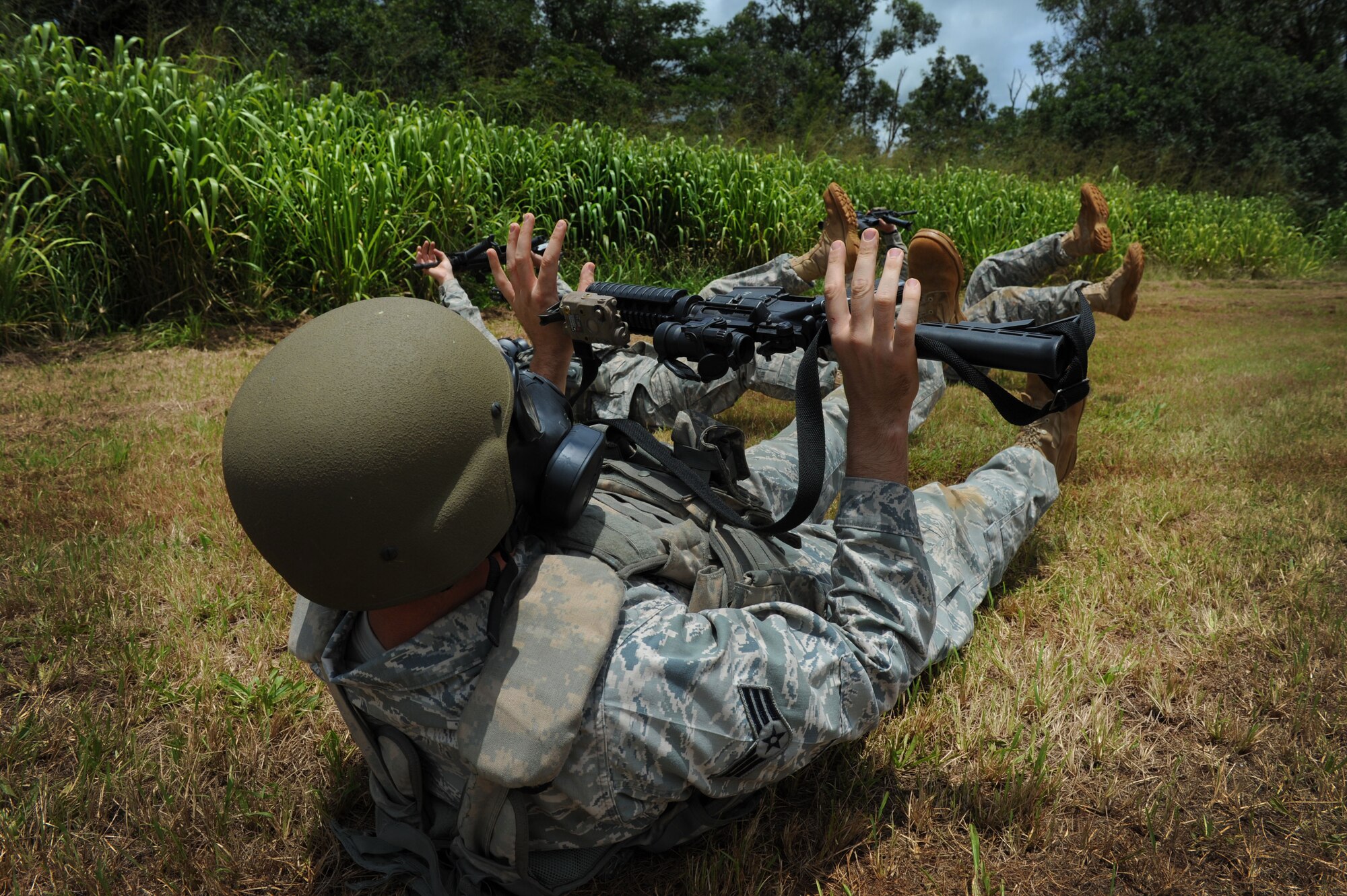 Members of the 647th Security Forces Squadron Rodeo team perform flutter kicks while holding up their M4 rifles and wearing gas masks at the firing range on Scholfield Barracks June 13. The 647th SFS Rodeo team consists of four members who must endure physical and mental challenges to ready themselves for the Rodeo competition. (U.S. Air Force photo/Senior Airman Lauren Main)