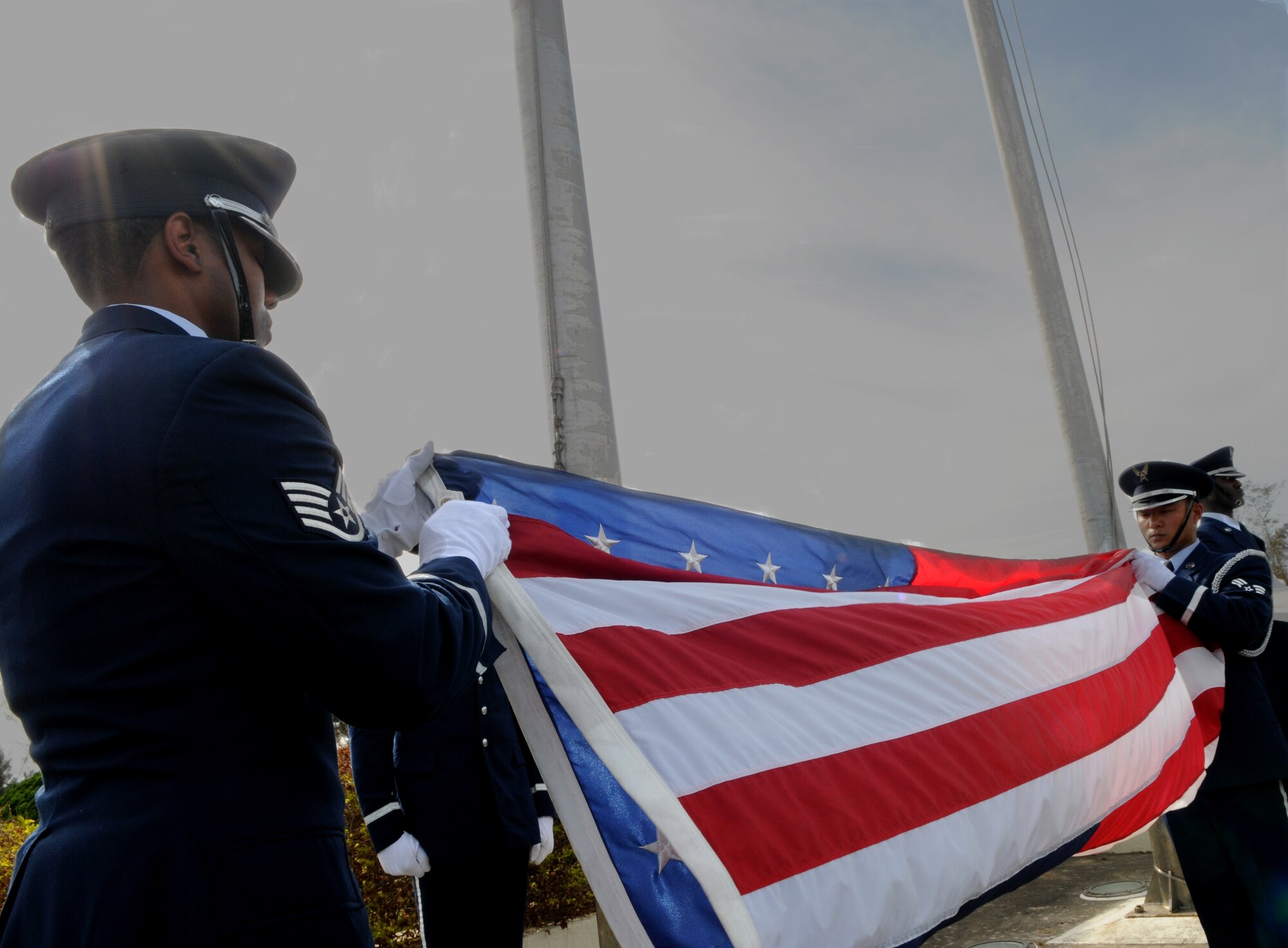 Kadena Honor Guardsmen Staff Sgt. Mario Rainge, 18th Civil Engineer Squadron, and Senior Airman Raymond Firme, 18th Component Maintenance Squadron, fold the American flag during the 2011 Air Force Sergeants Association’s Flag Day Ceremony, June 14, Kadena Air Base, Japan. During this ceremony out of service flags were retired by being burned. (U.S. Air Force photo/Airman1st Class Jarvie Z.Wallace) 