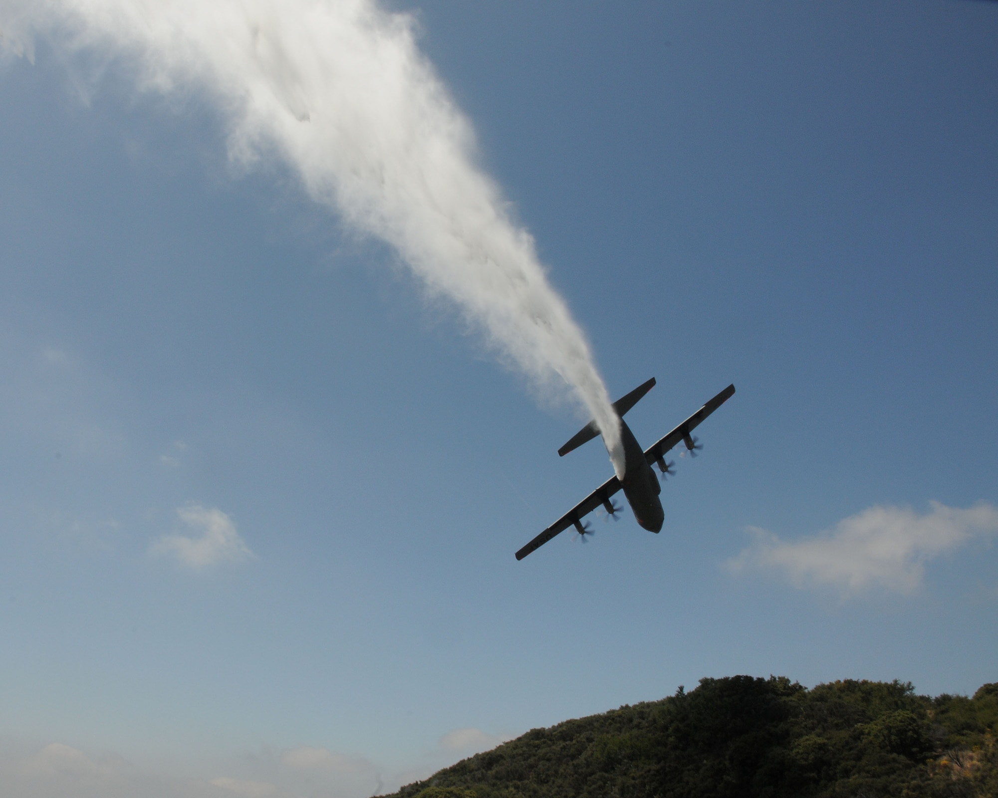 A C-130J from the 146th Airlift Wing, California Air National Guard, drops water over the Angeles Forest during Modular Airborne Firefighting System (MAFFS) training held June 7, 2011. The aircrews follow a U.S. Forest Service lead plane and demonstrate proficiency by dropping over a designated area. (Photo by Master Sgt. Dave Buttner)
