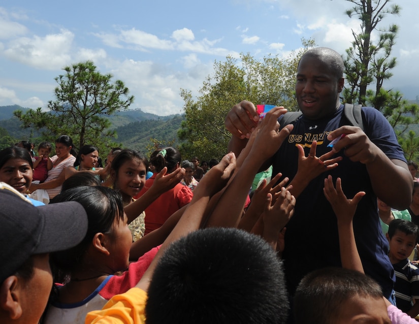 Petty Officer 2nd Class Corey Johnson, from Joint Task Force-Bravo, hands out candy to children June 11, 2011, at an isolated village near Comayagua, Honduras. More than 120 JTF-B members from Soto Cano Air Base, Honduras, hiked two miles up steep terrain to deliver food to people living in the town. All ranks of JTF-Bravo members chipped in nearly $1,700 for the food. (U.S. Air Force photo/Tech. Sgt. Matthew McGovern)