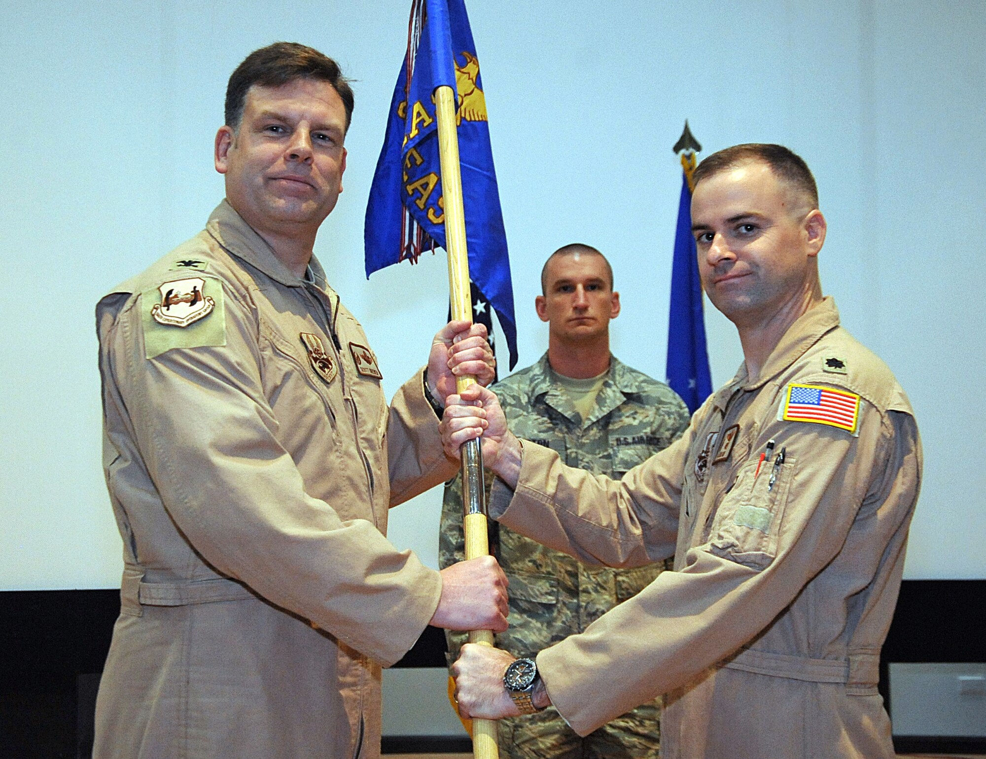 Col. Scott Brewer, 386th Expeditionary Operations Group commander, left, passes the 737th Expeditionary Airlift Squadron guide-on to Lt. Col. Jon Julian June 13 during a change of command ceremony at an undisclosed location in Southwest Asia. Colonel Julian assumed command of the 737th EAS from Lt. Col. Eric Halverson. (U.S. Air Force photo by Senior Airman Cynthia Spalding)